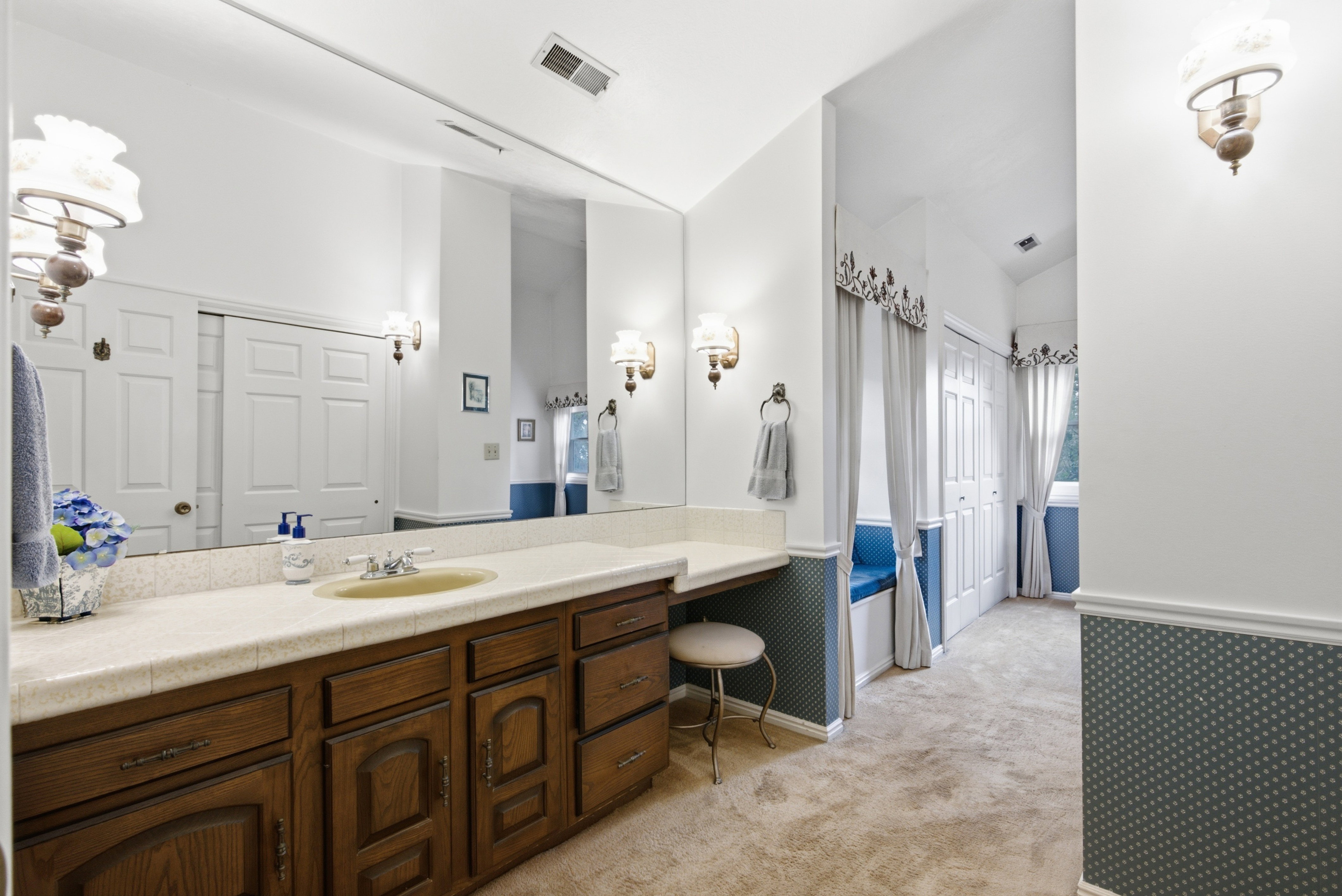 Vanity area featuring a long countertop, extensive wood cabinetry, and a large wall-mounted mirror