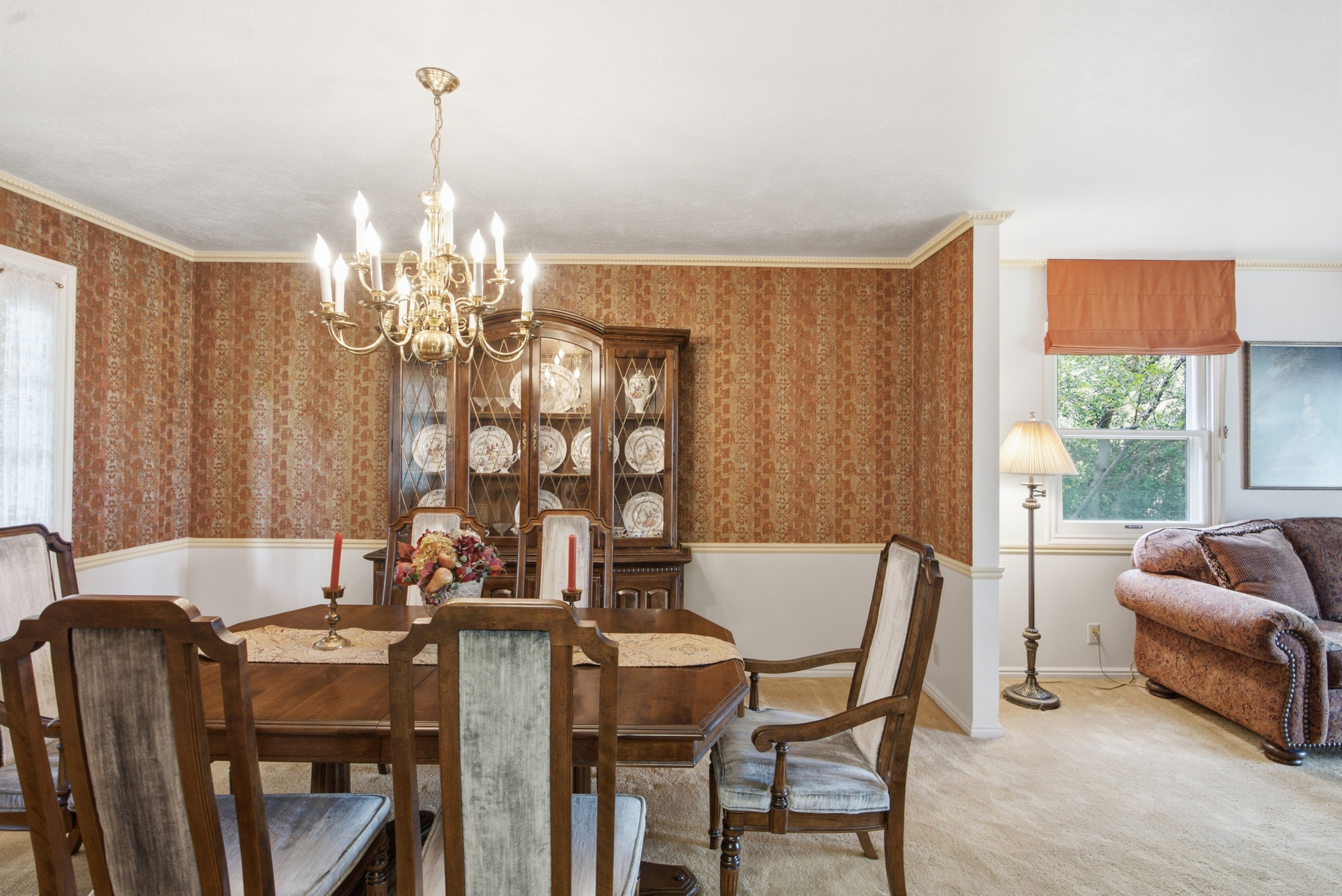 Dining area featuring a brass chandelier, patterned wallpaper, and white chair rail molding