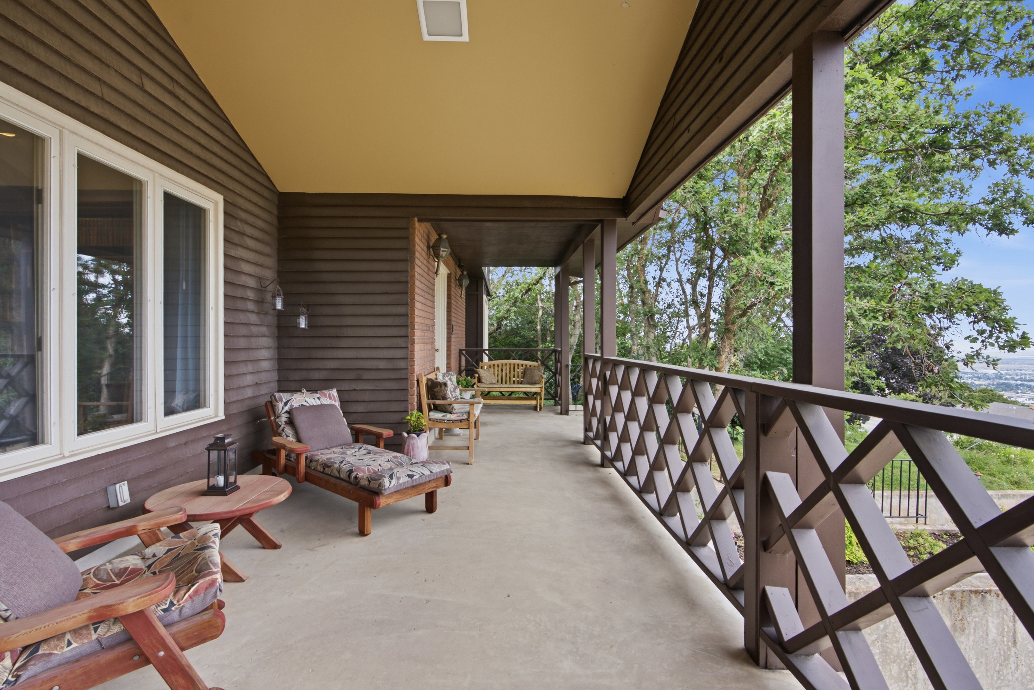 Expansive covered porch featuring wood-finish siding, a decorative railing, and recessed lighting
