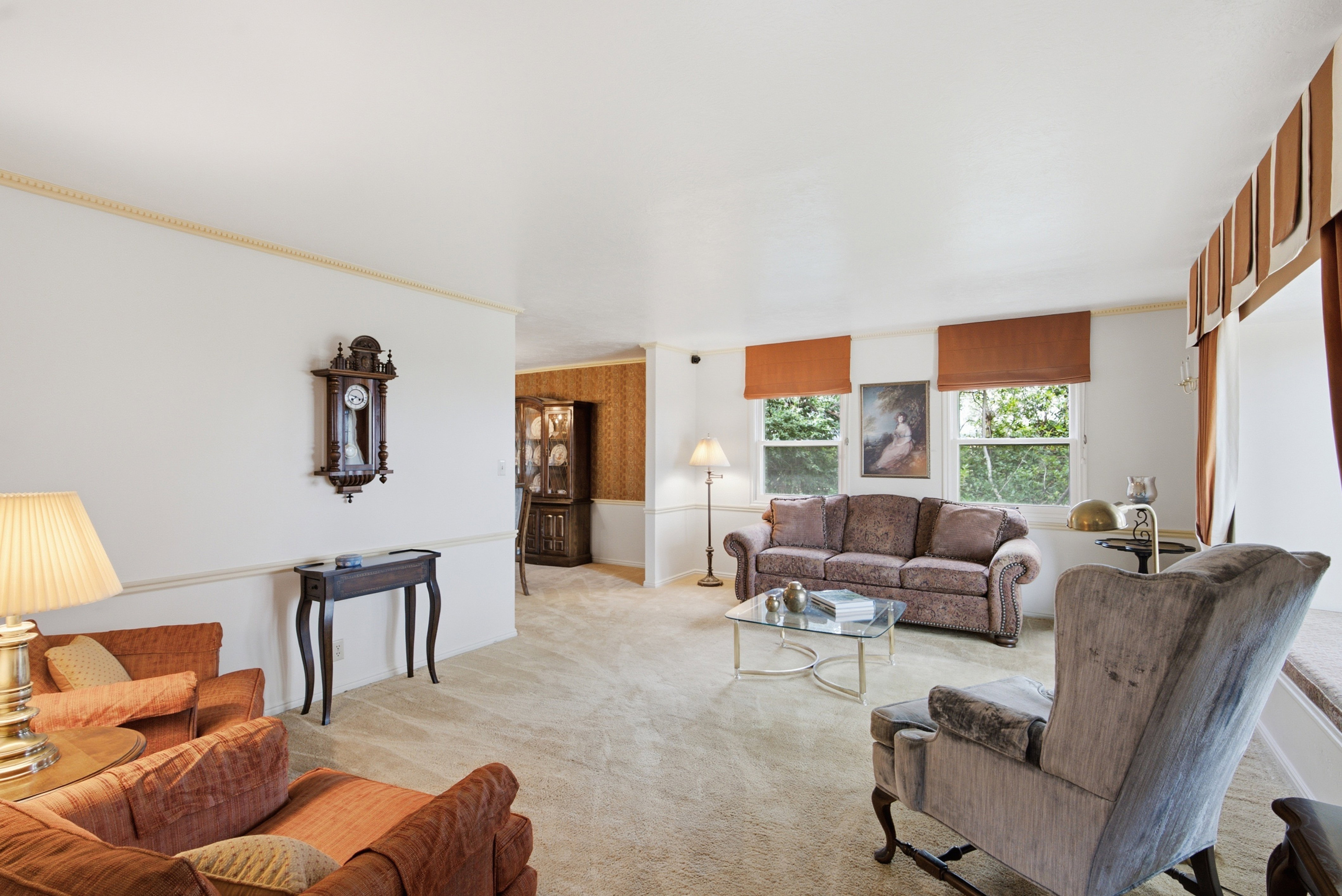 Spacious living area featuring light-toned carpeting and white walls with decorative molding
