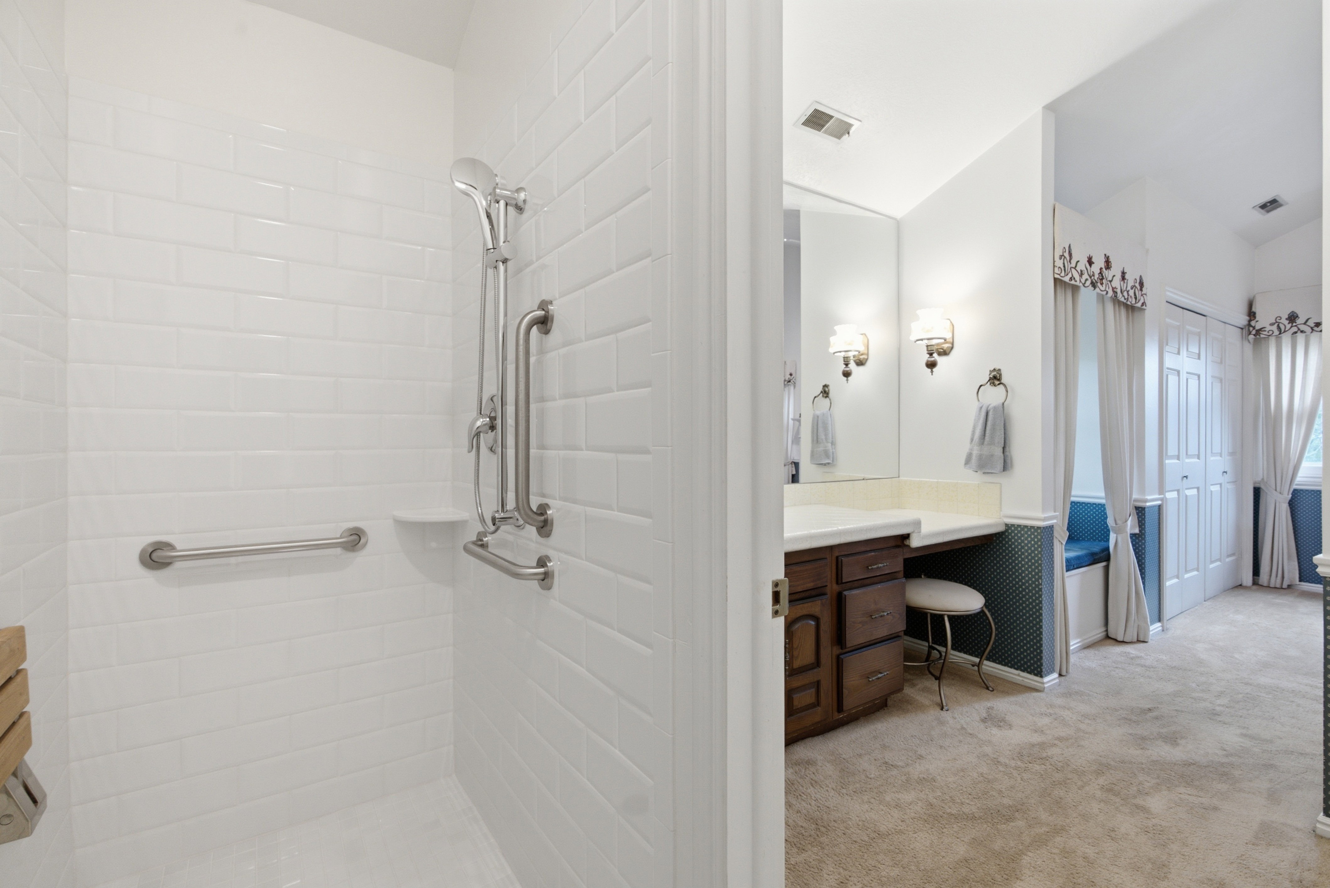 White subway tile shower with a handheld shower fixture, grab bars, and a built-in shower niche