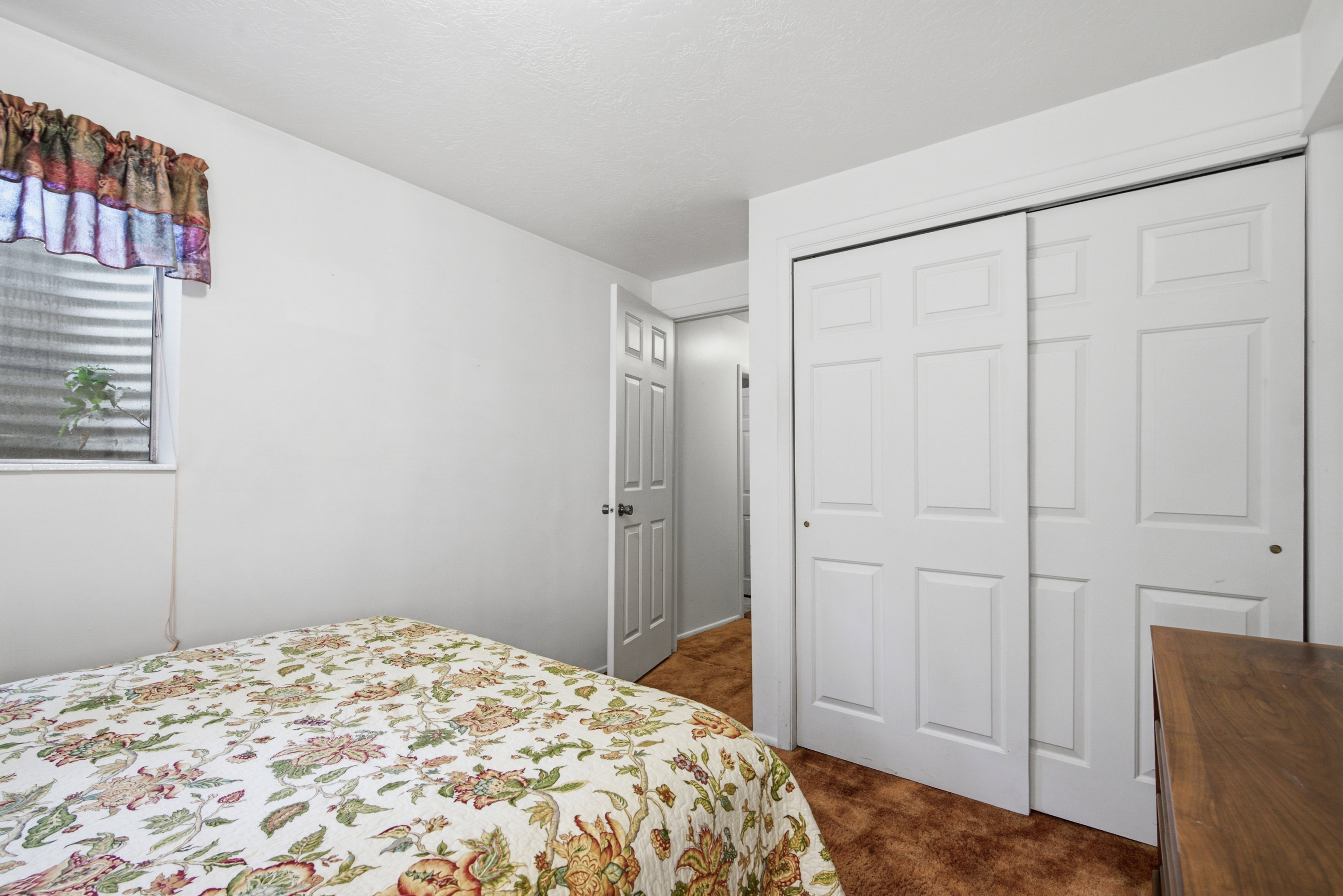 Carpeted room with a small window featuring horizontal blinds