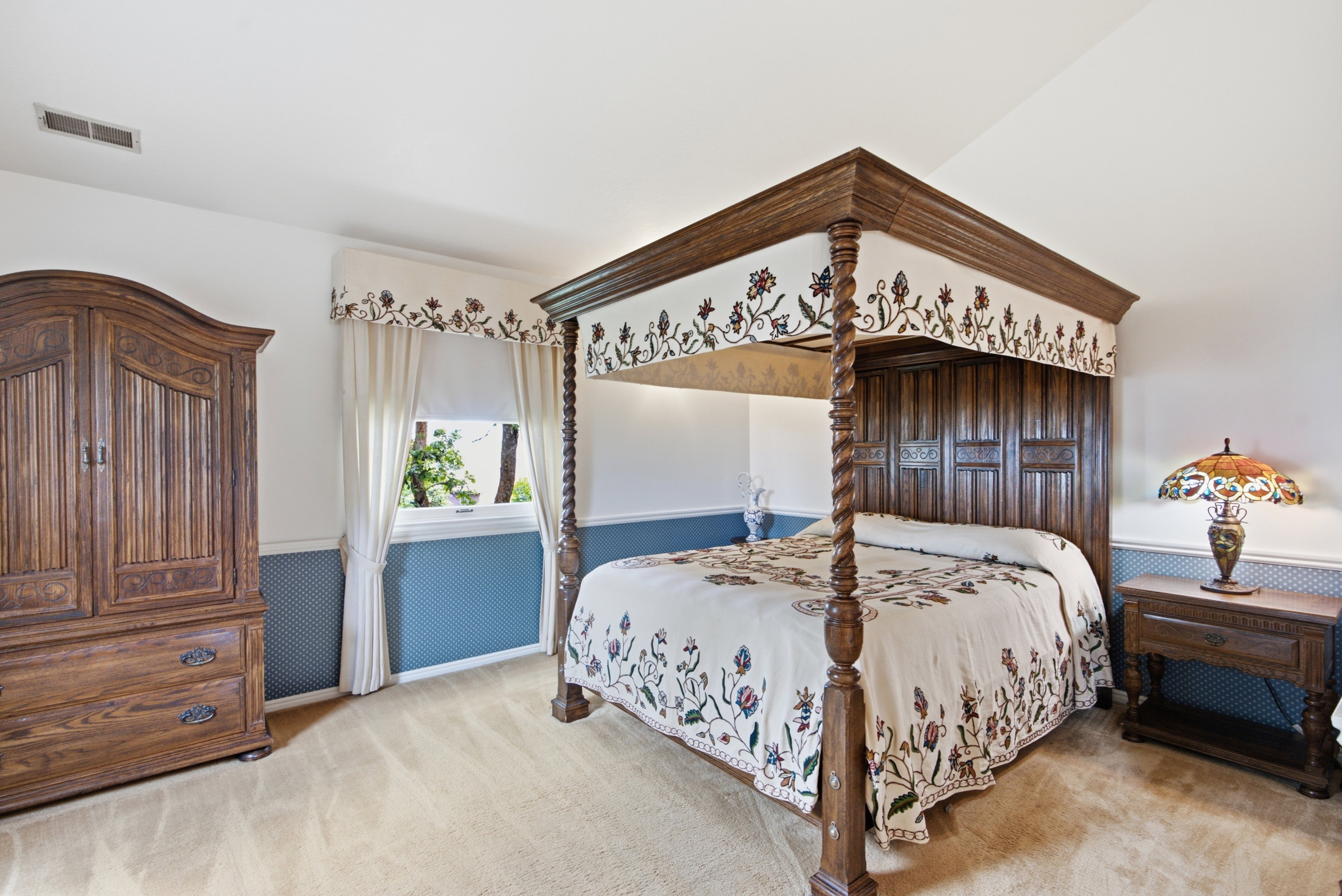 Carpeted room featuring a window with white blinds and curtains, a built-in air vent, and two-tone walls with patterned wainscoting