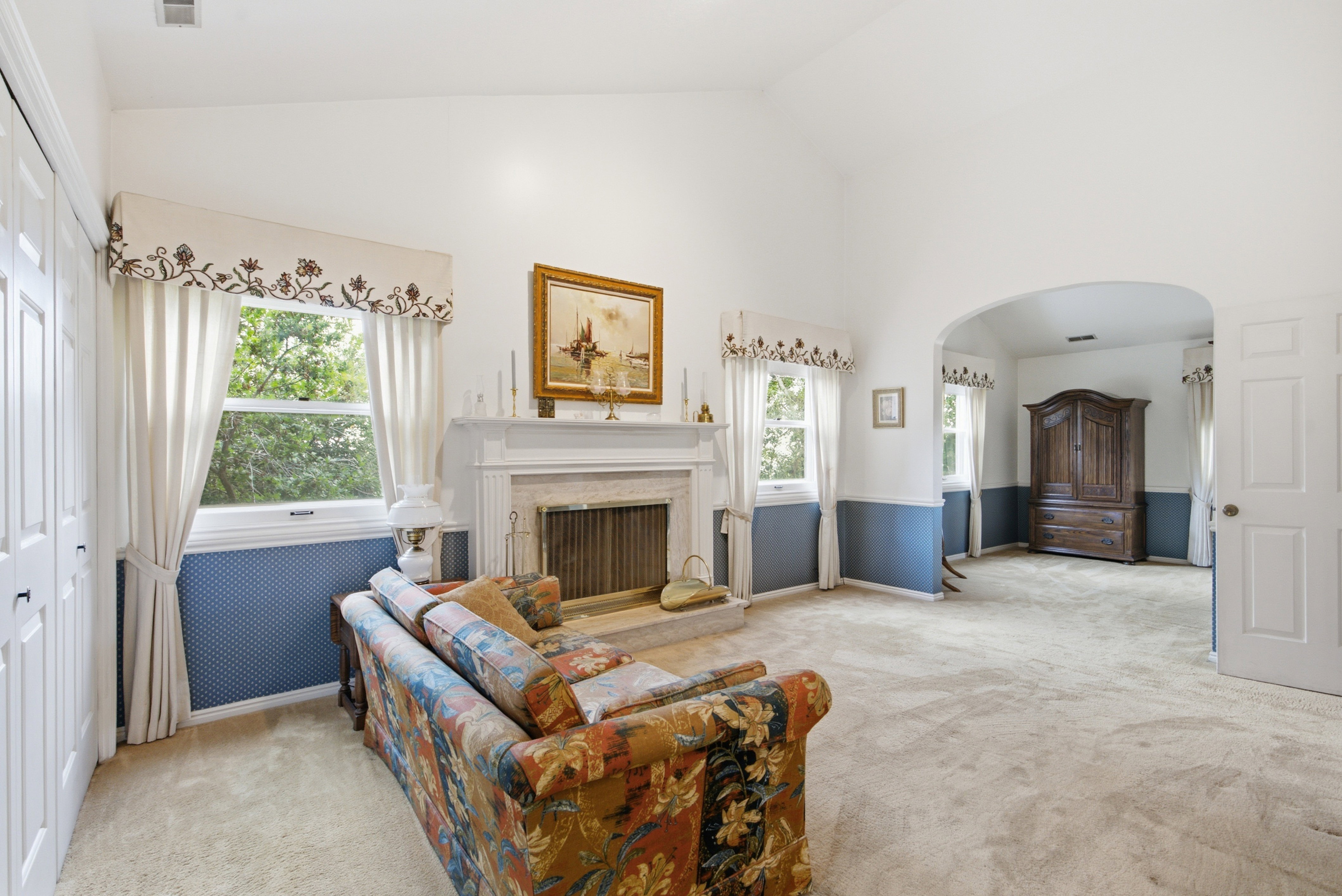Spacious interior featuring a vaulted ceiling and a central fireplace with a decorative mantel