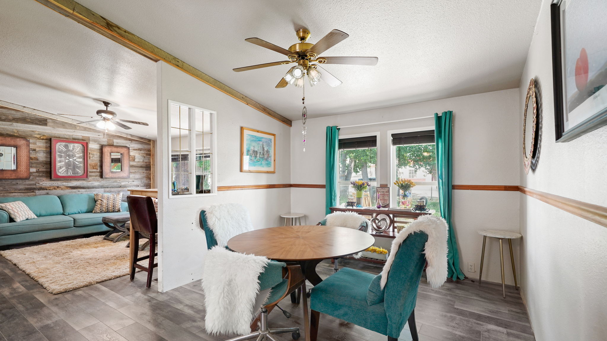 Open-concept interior featuring wood-finish flooring, a ceiling fan, and a dining area with natural light