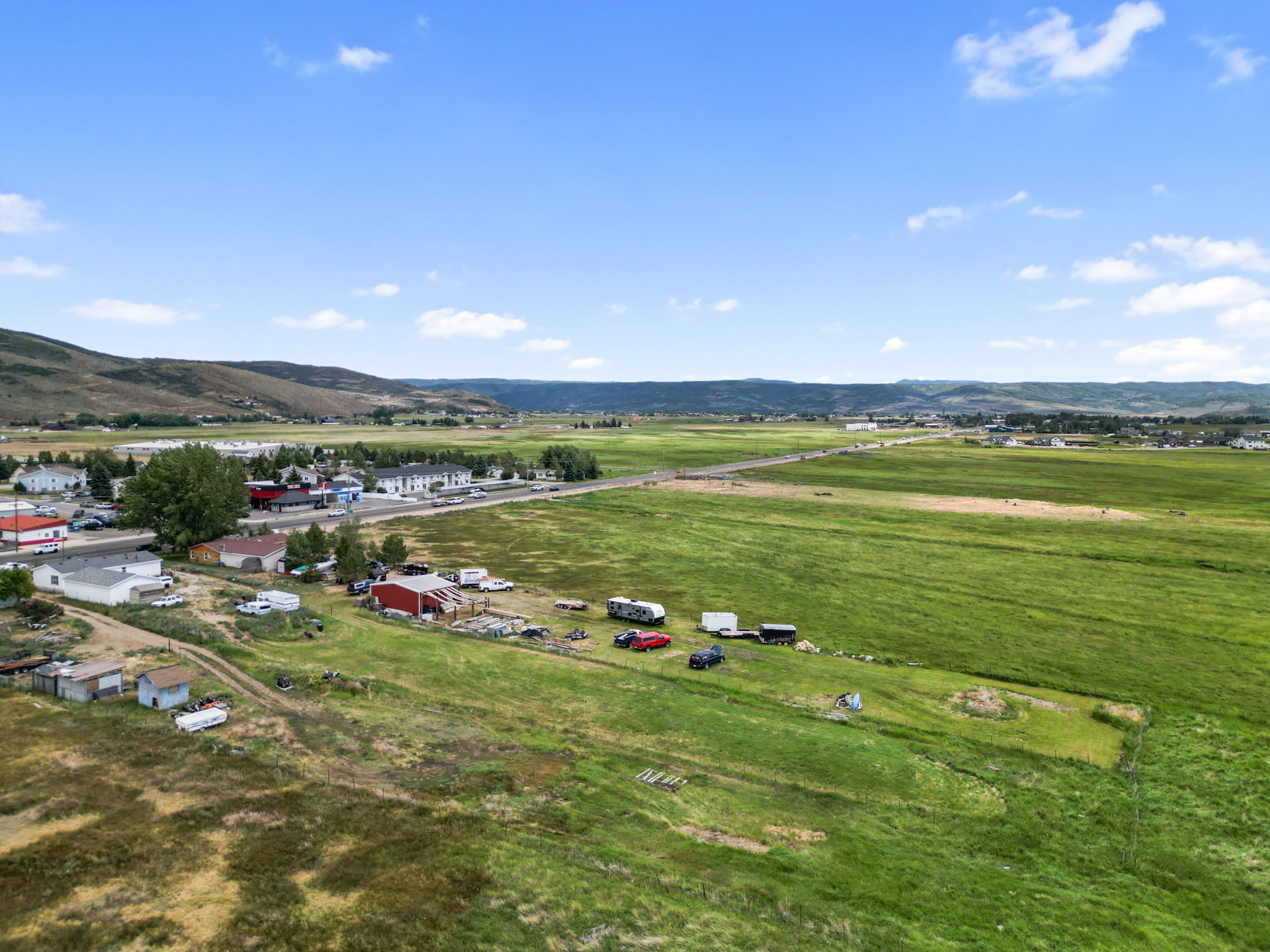 Expansive rural landscape featuring vast green fields and distant rolling hills