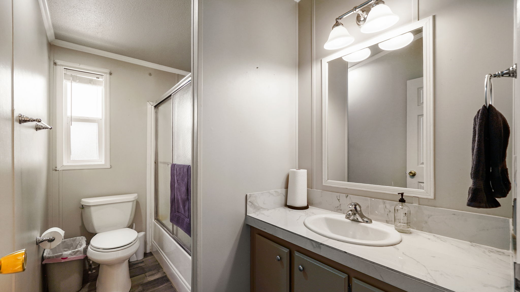 Bathroom featuring a vanity with a white countertop and integrated sink, a framed mirror, and a three-light vanity fixture