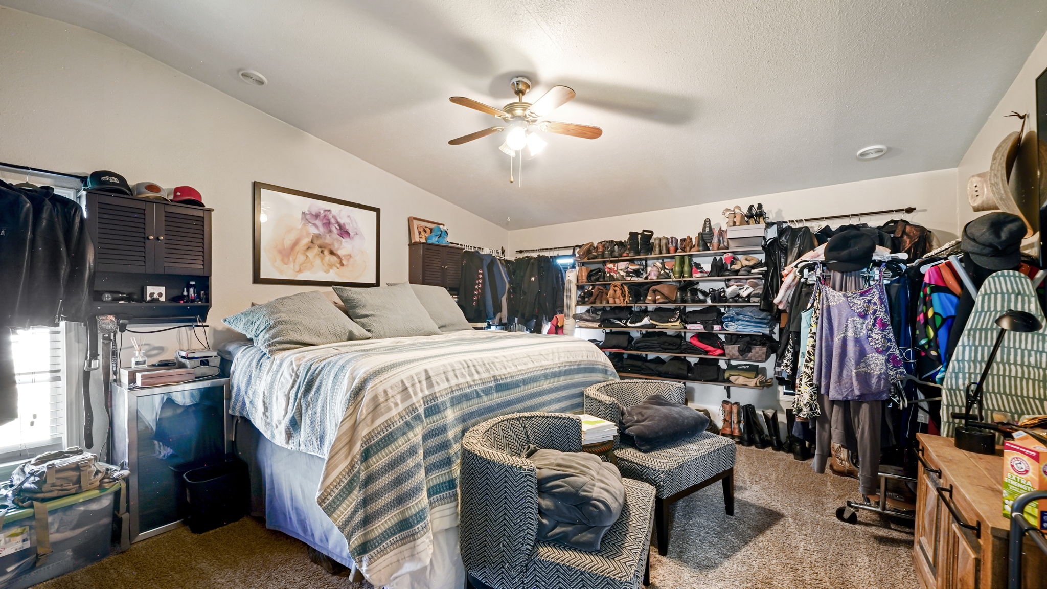 Spacious room featuring vaulted ceilings, a ceiling fan with light, and carpet flooring