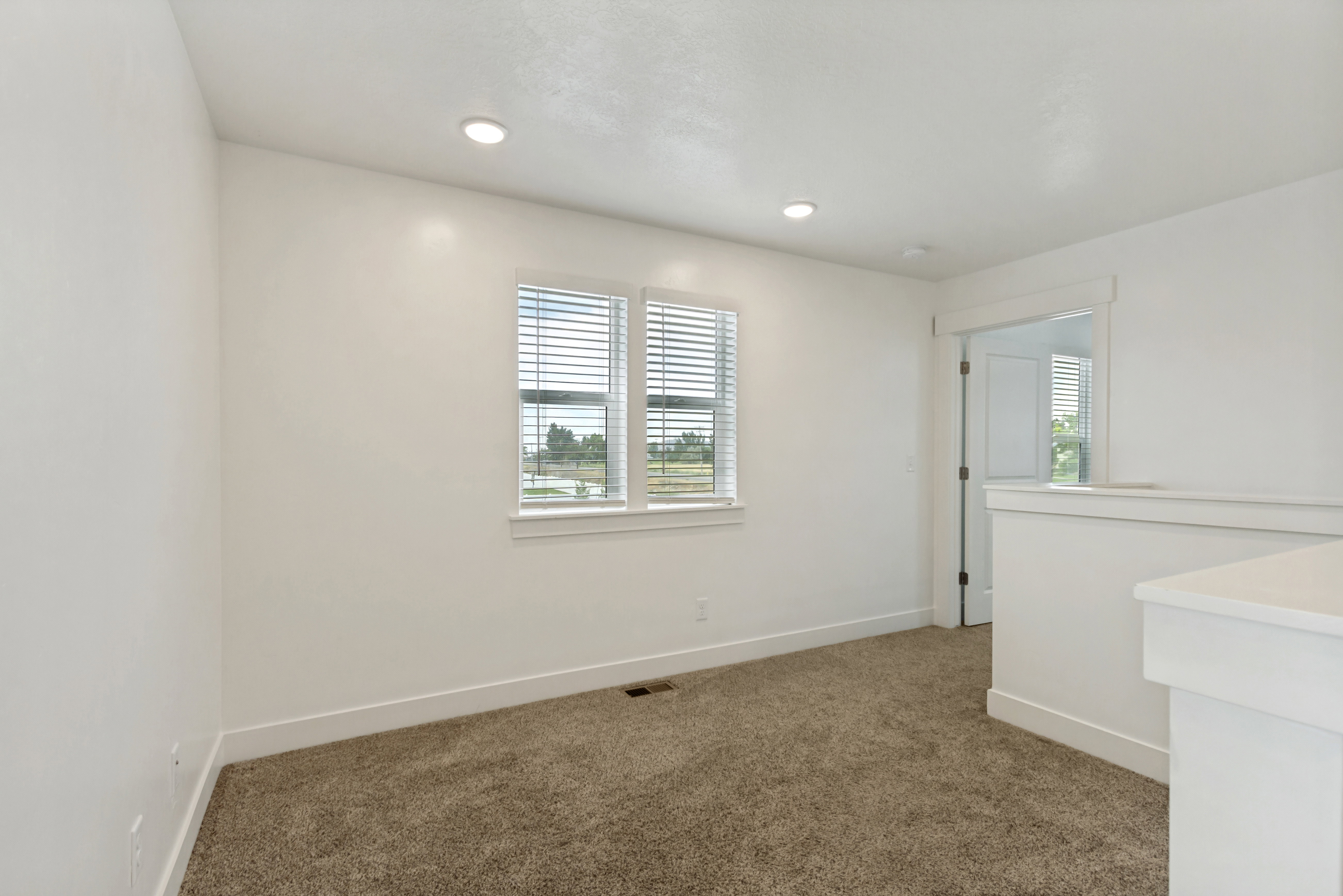 Loft featuring white walls, recessed lighting and two large windows
