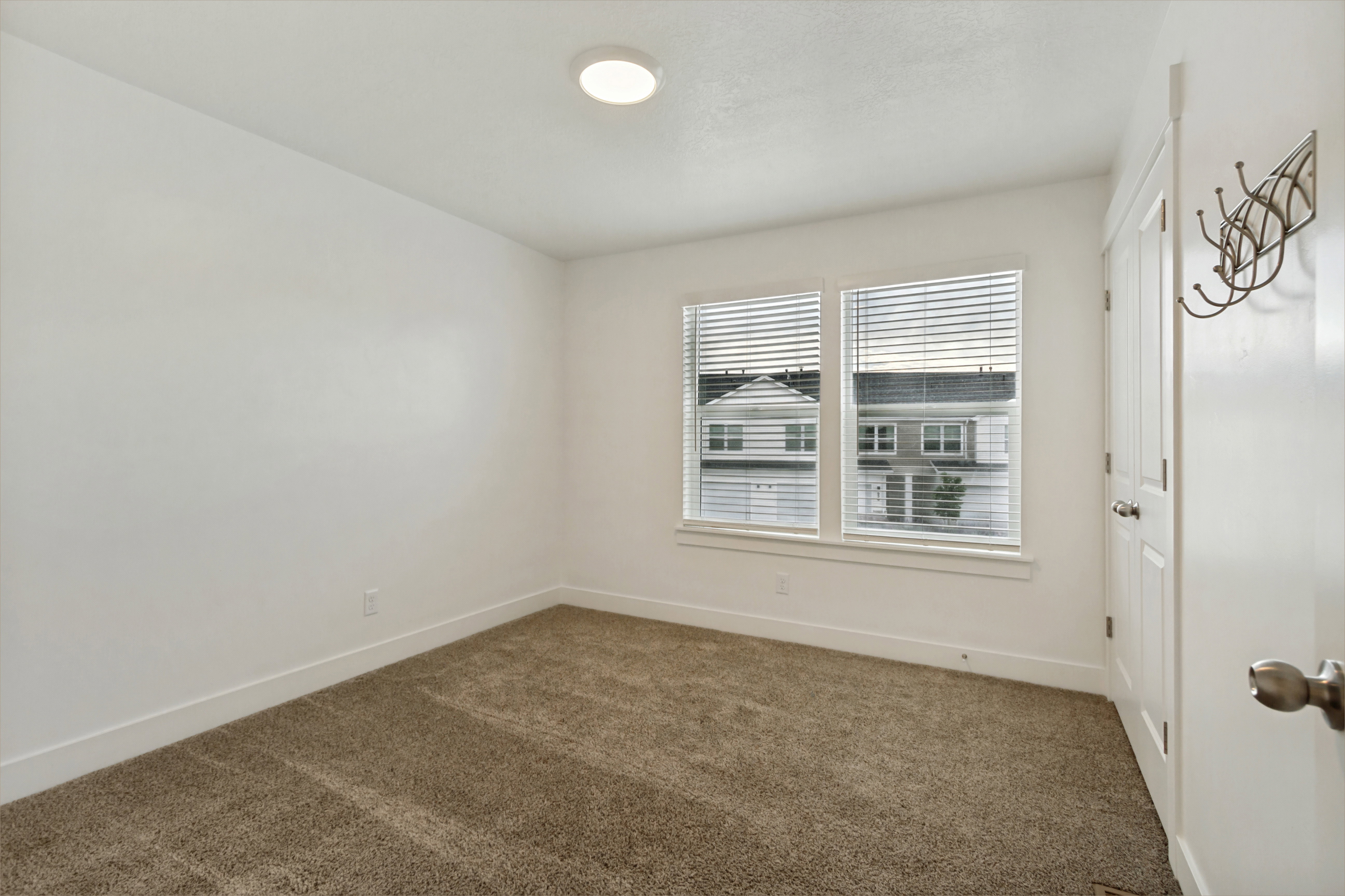 Bedroom three, 2 tone wall finishes, two pane windows, light brown carpet, white baseboards, and a flush mount ceiling light fixture