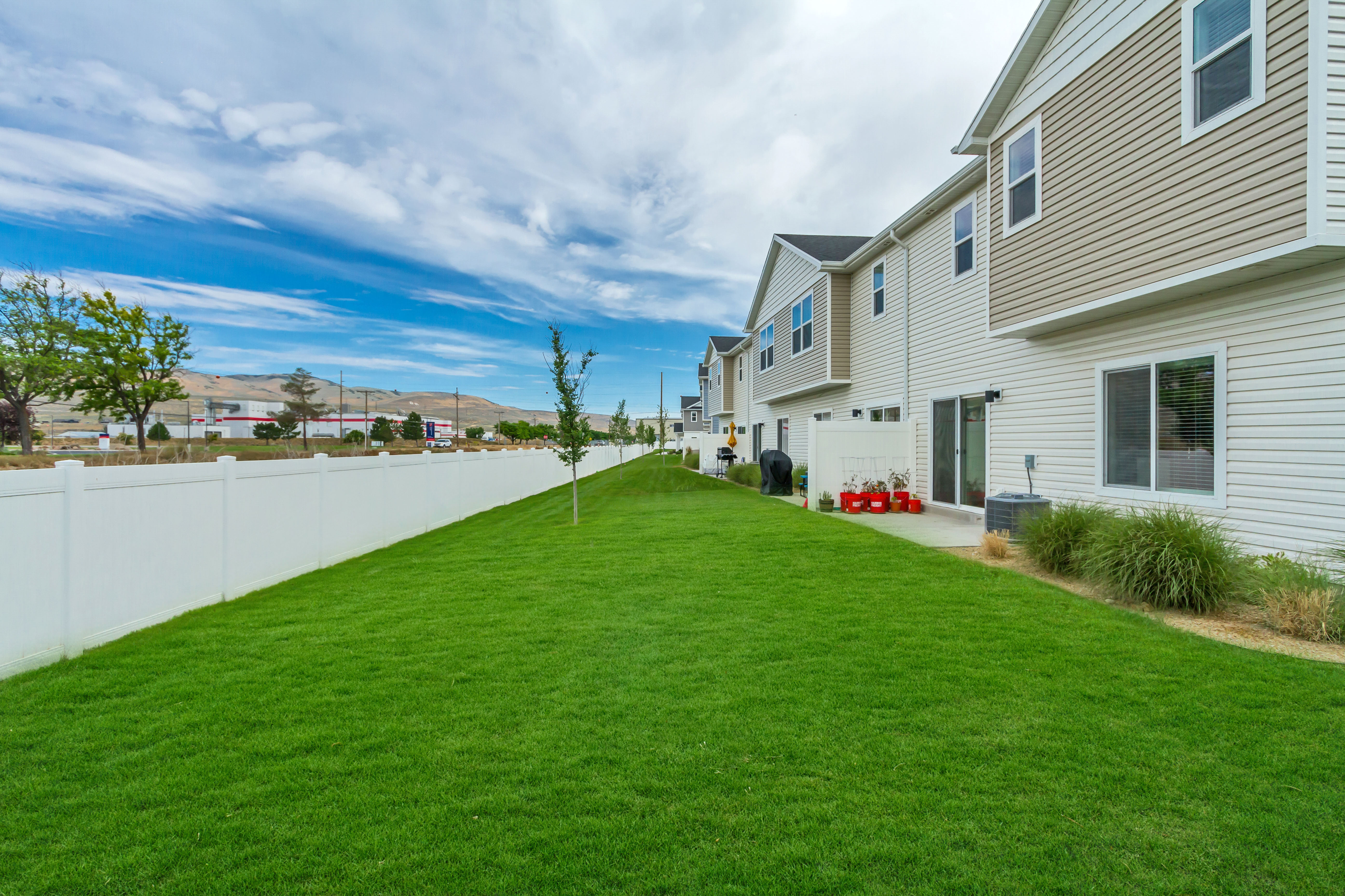 End unit, no backyard neighbors featuring a spacious green lawn with a concrete patio directly accessible via two sliding glass doors