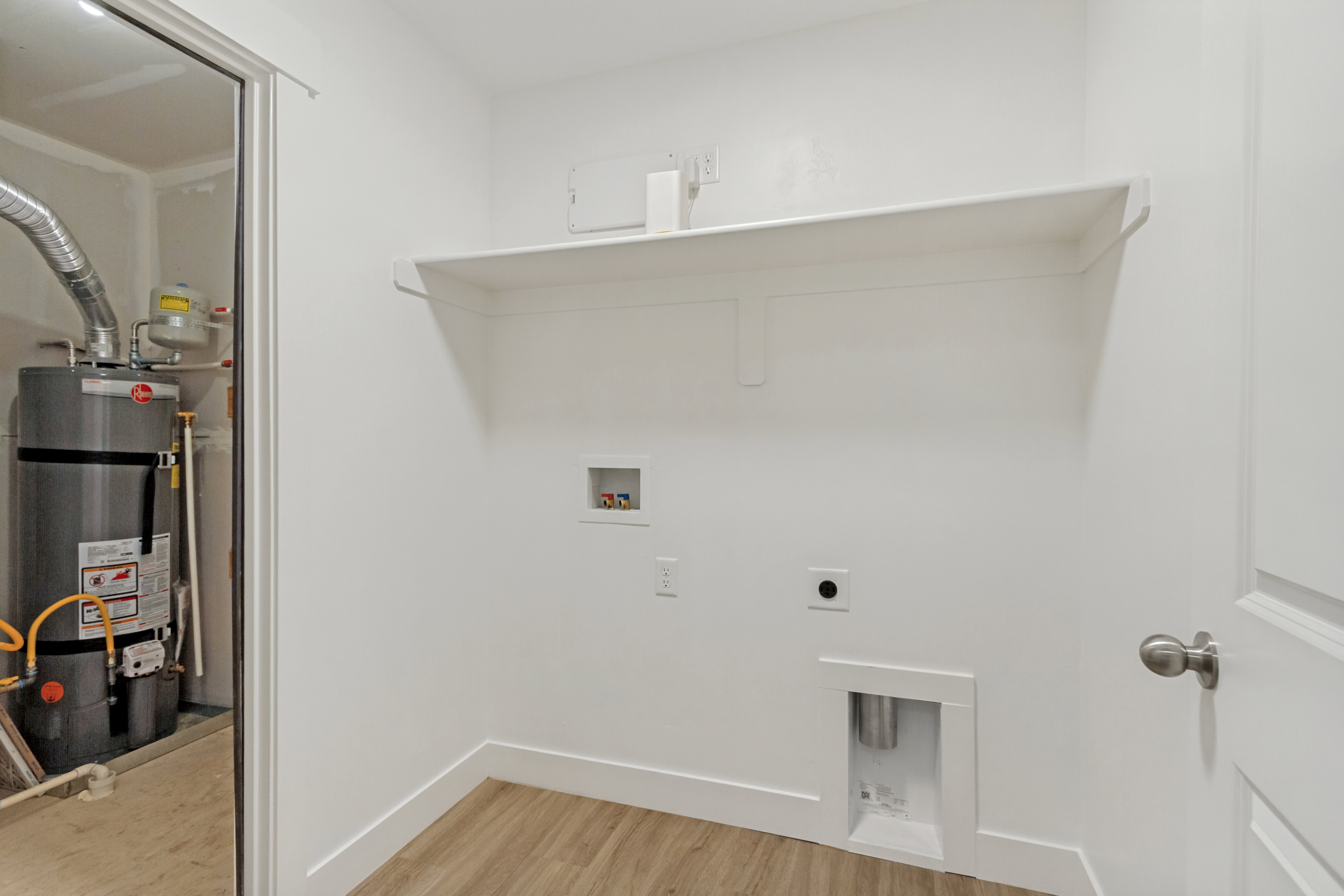 Dedicated utility space featuring laundry hookups, a built-in shelf, and wood-finish flooring