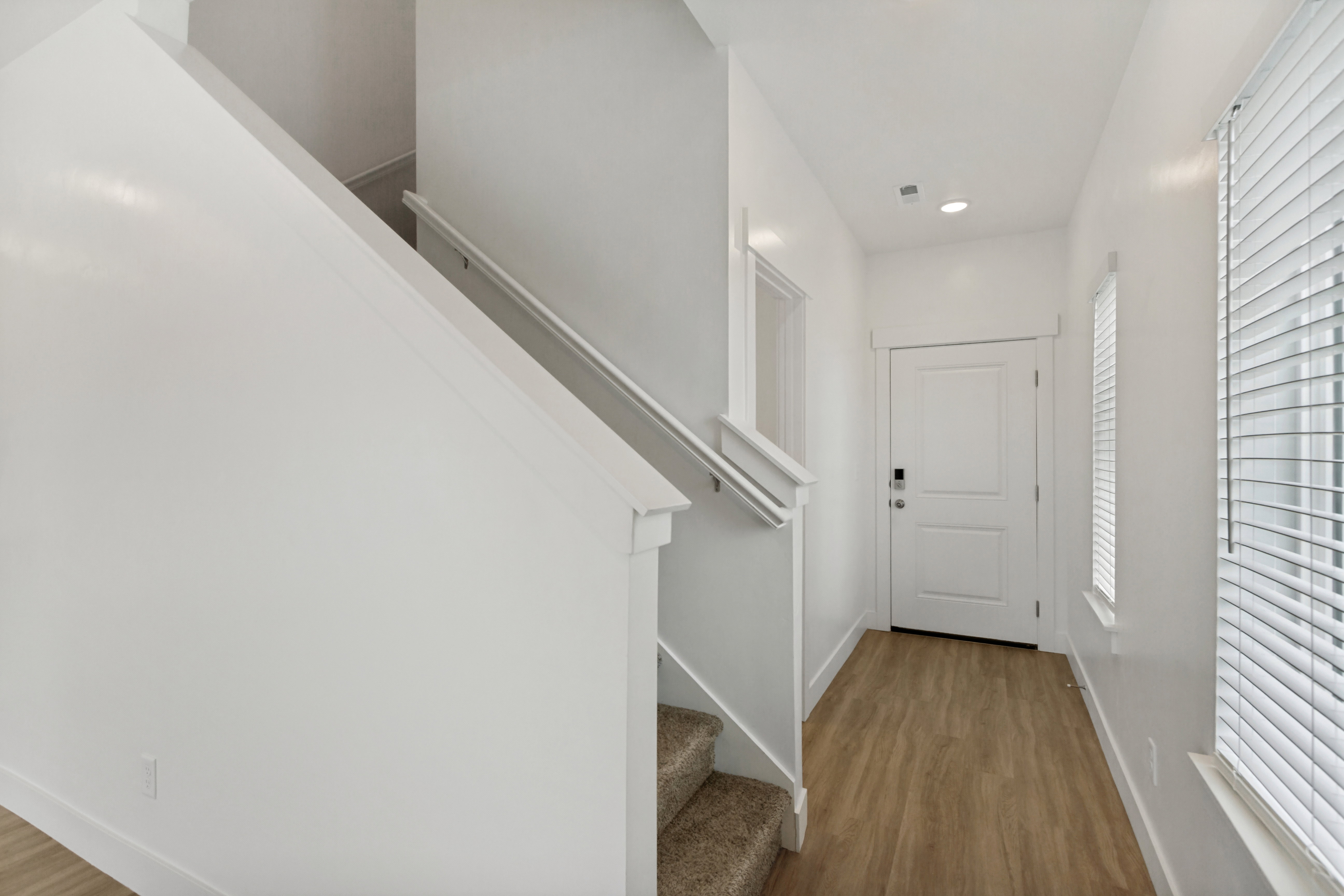 Foyer featuring wood-finish flooring, white paneled entry door, recessed lighting, and a staircase to the upstairs