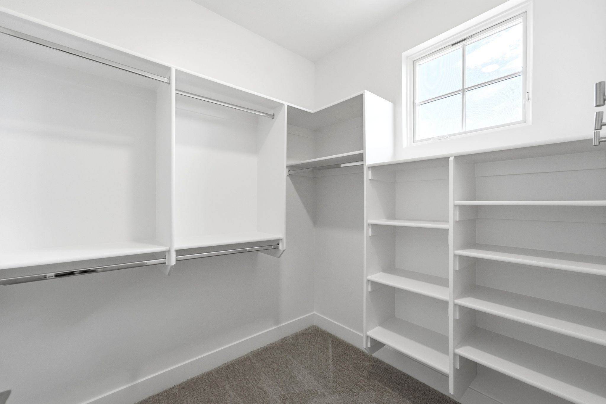 Custom closet system featuring white shelving and chrome hanging rods