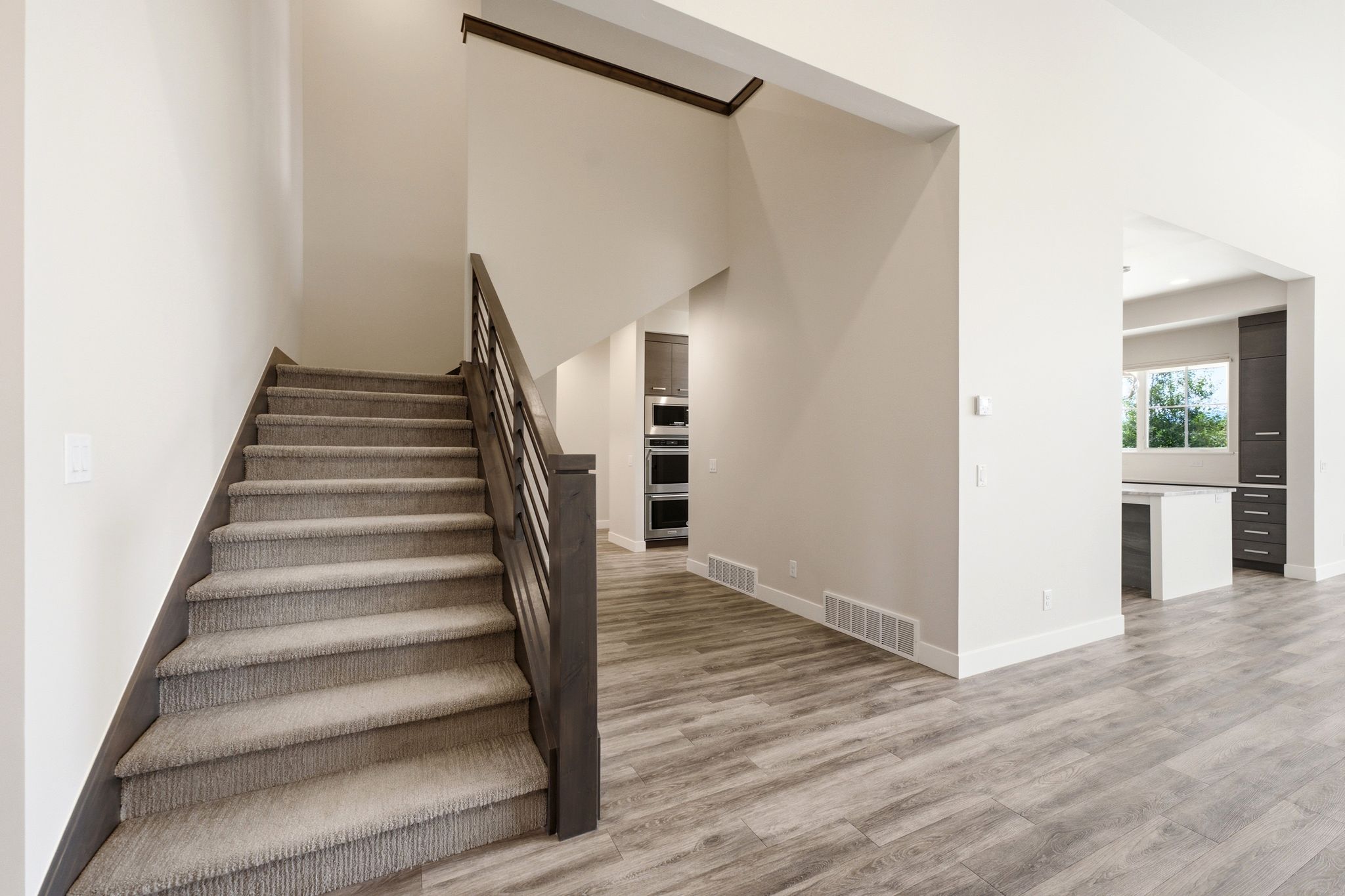 Carpeted staircase with dark wood-finish handrail and black metal balusters