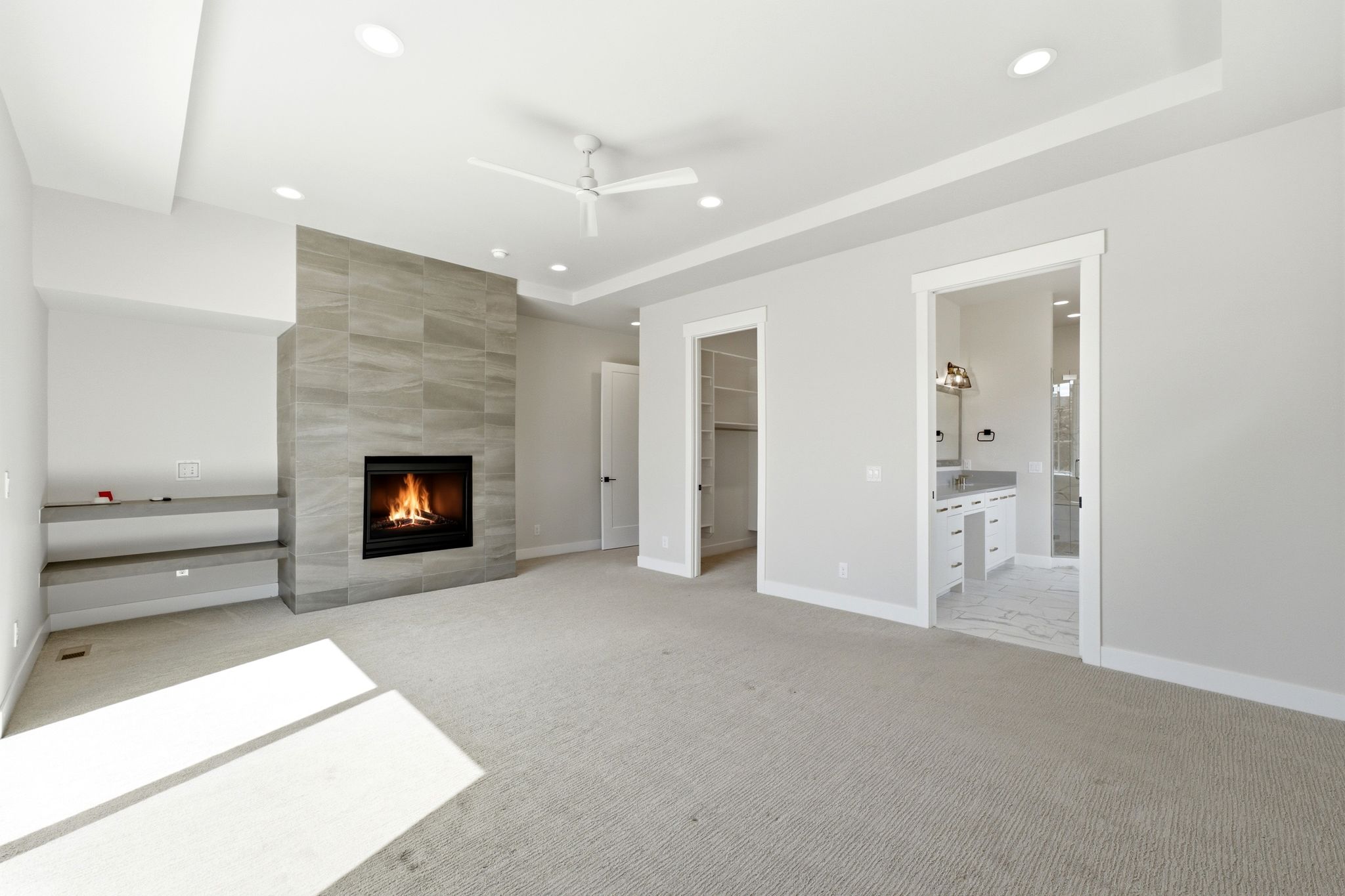 Spacious room featuring a floor-to-ceiling tiled fireplace, built-in shelving, recessed lighting, and a ceiling fan