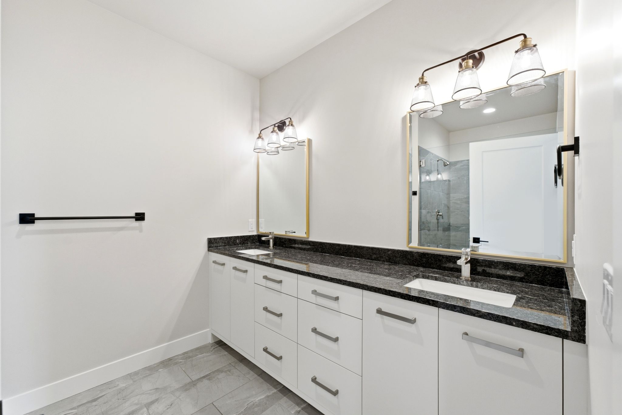 Double vanity with white cabinetry, dark stone countertop, and two integrated rectangular sinks