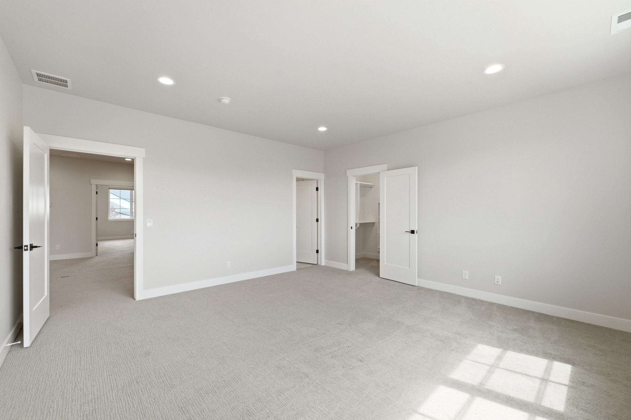 Spacious room with light gray carpeting and white walls