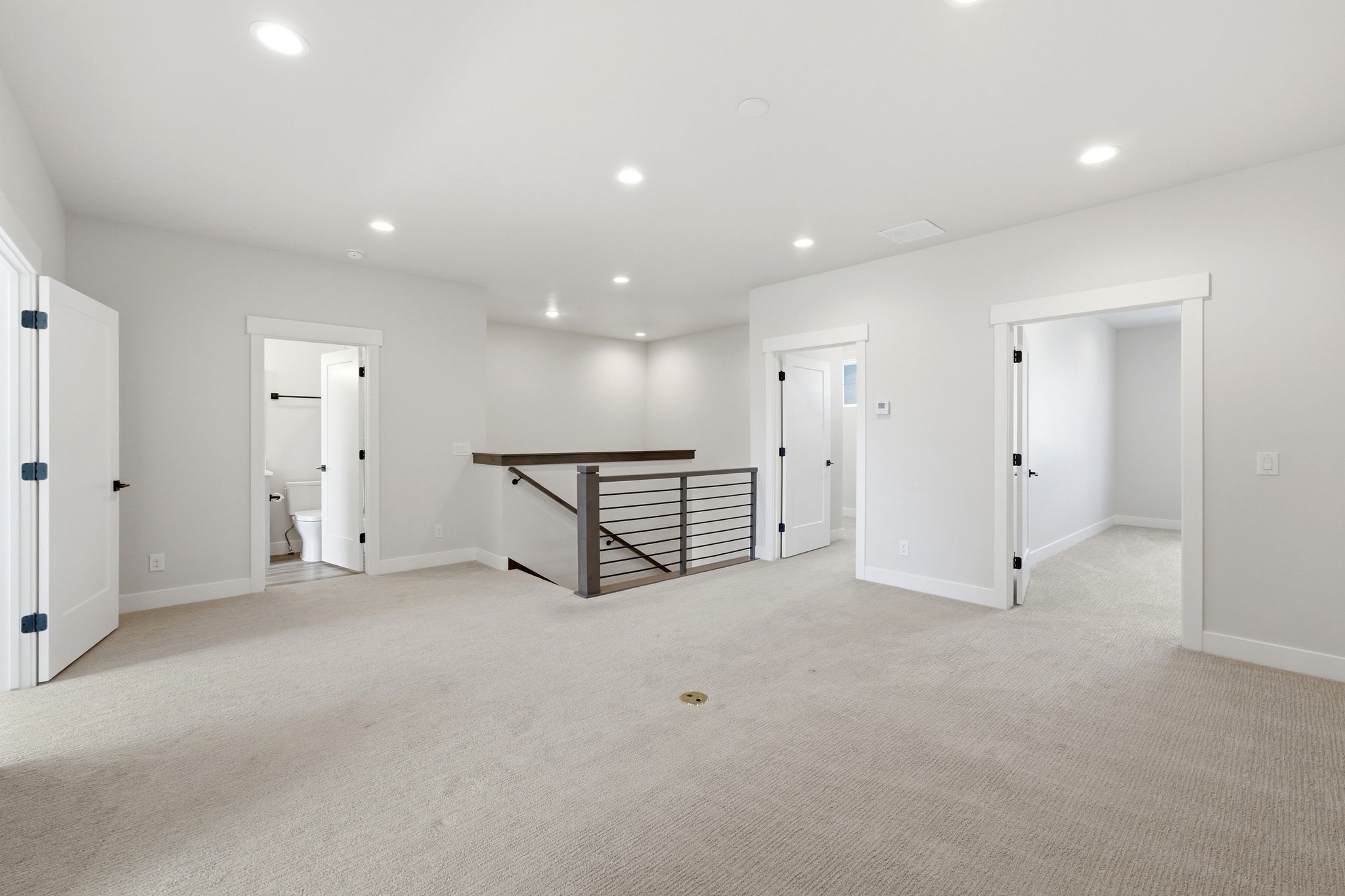 Second-story landing featuring recessed lighting, light neutral carpet flooring, and a contemporary horizontal metal baluster railing