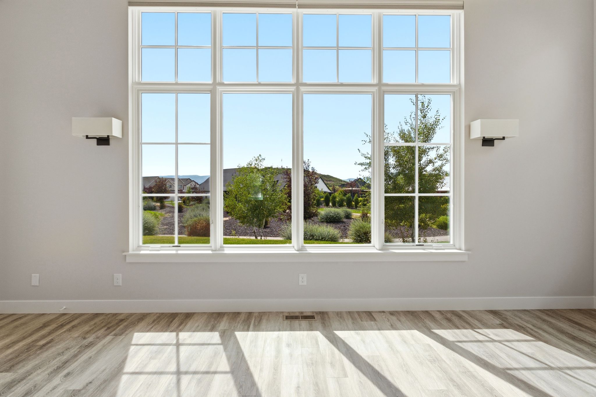 Expansive multi-pane window with white trim and a surrounding landscaped exterior