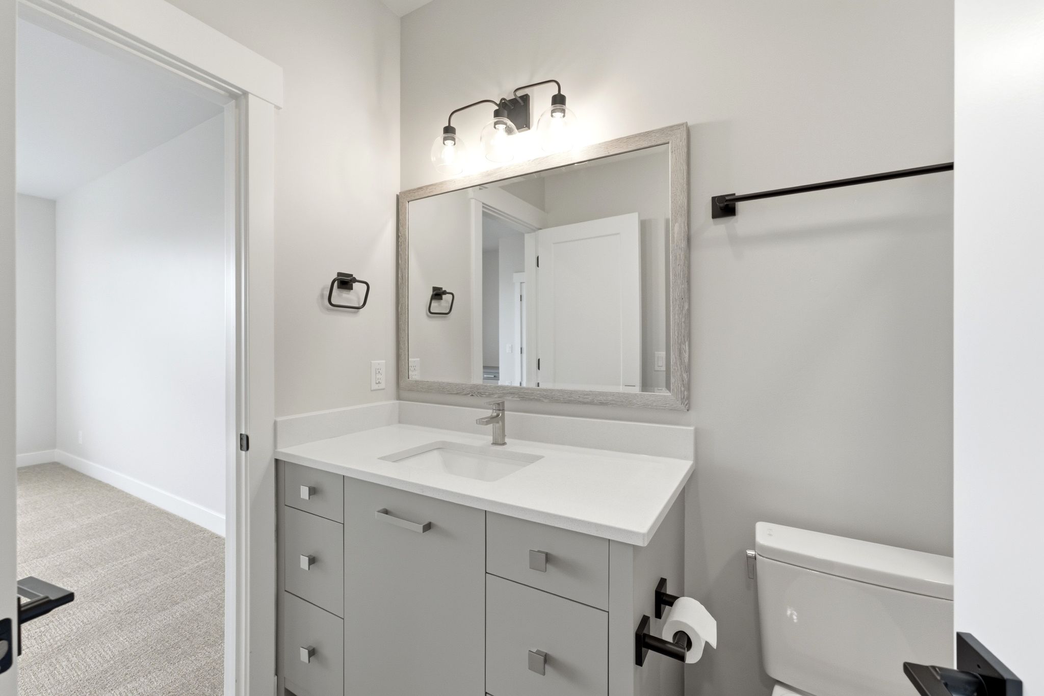 Bathroom featuring a single vanity with light gray cabinetry, white countertop, and contemporary brushed nickel faucet