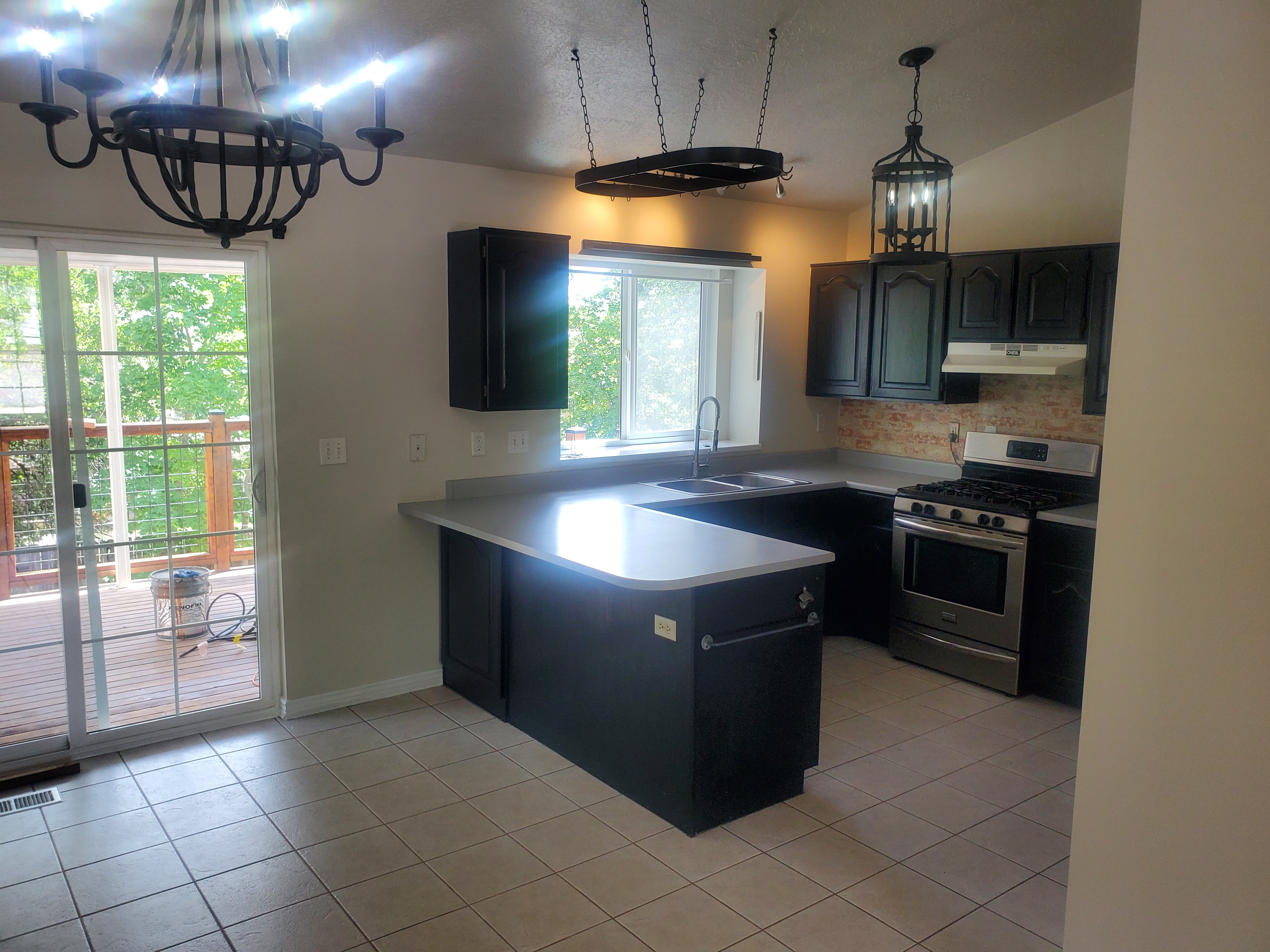 Kitchen featuring dark cabinetry, light-toned countertops, a stainless steel gas range, and a decorative tile backsplash