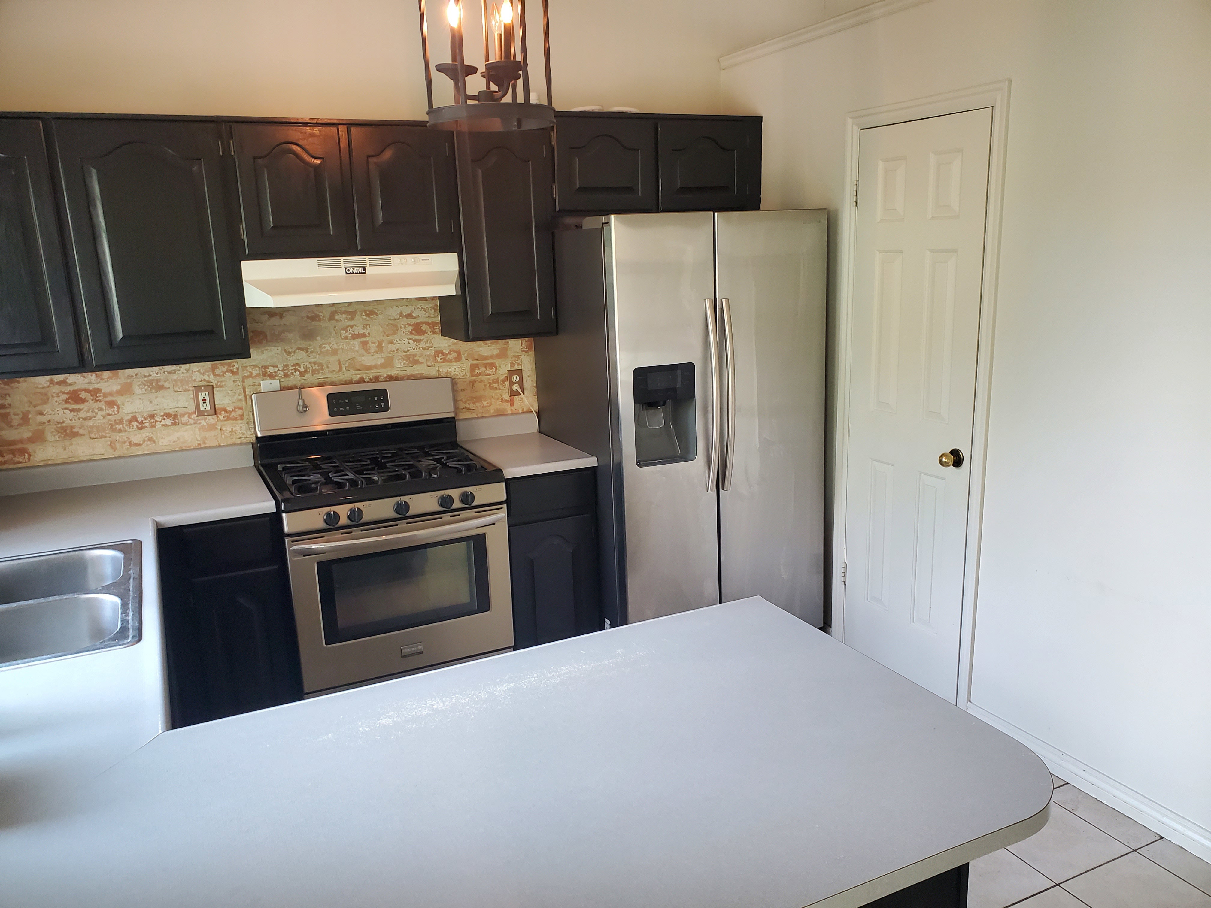 Kitchen featuring black cabinetry, stainless steel appliances, a gas range, and a brick-patterned backsplash