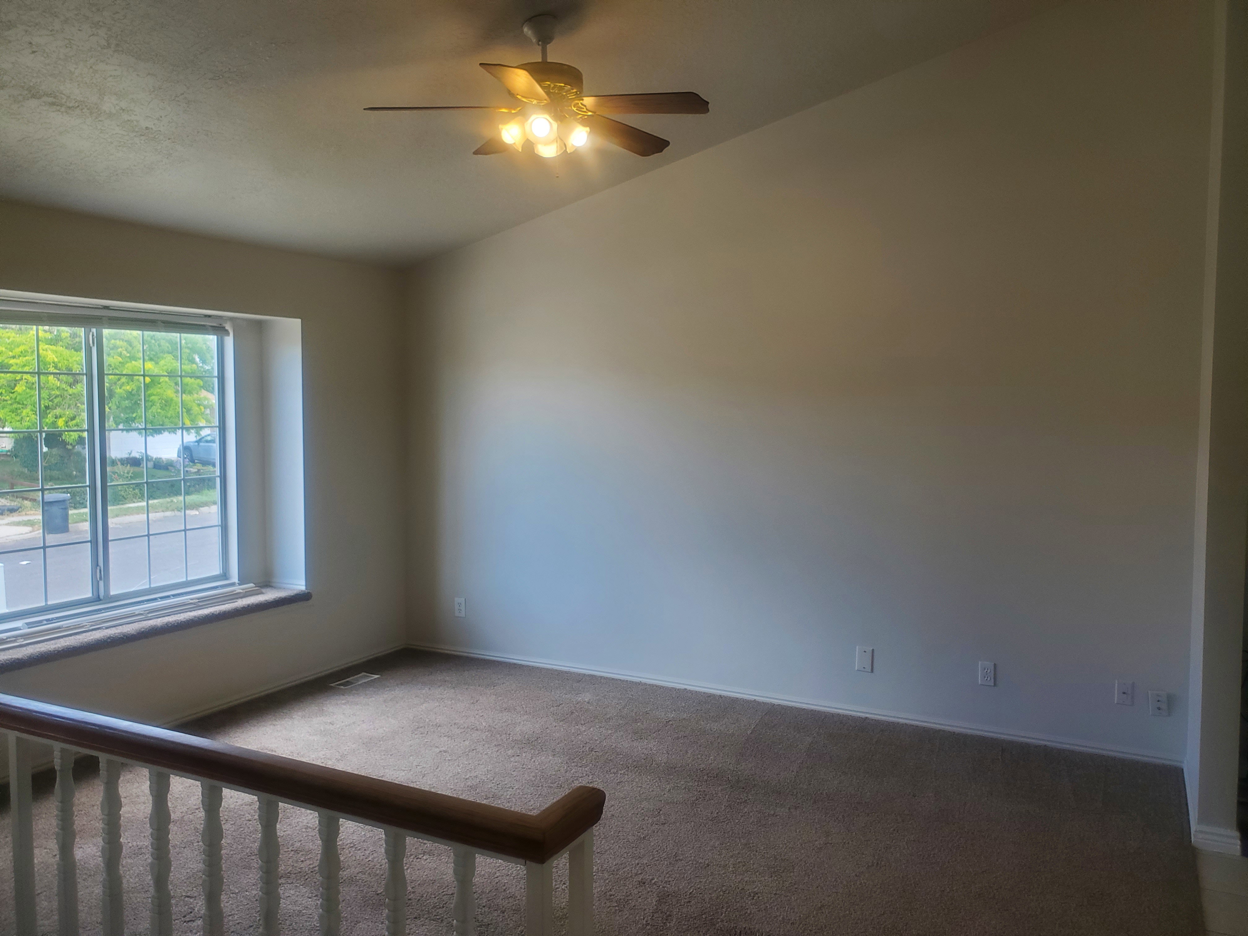 Carpeted room featuring a sloped ceiling and a ceiling fan with integrated lighting