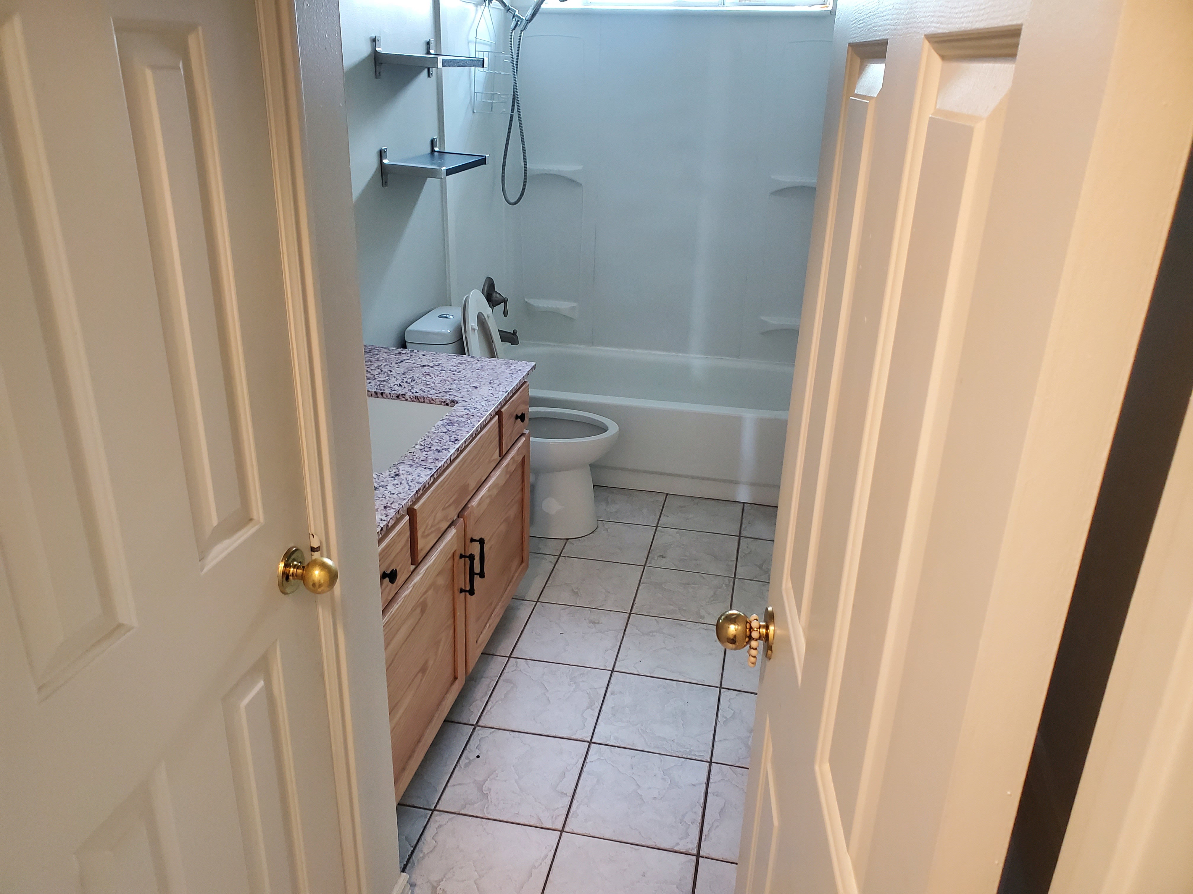 Bathroom featuring a wood vanity with dark hardware, a stone-finish countertop, an integrated sink, and tile flooring