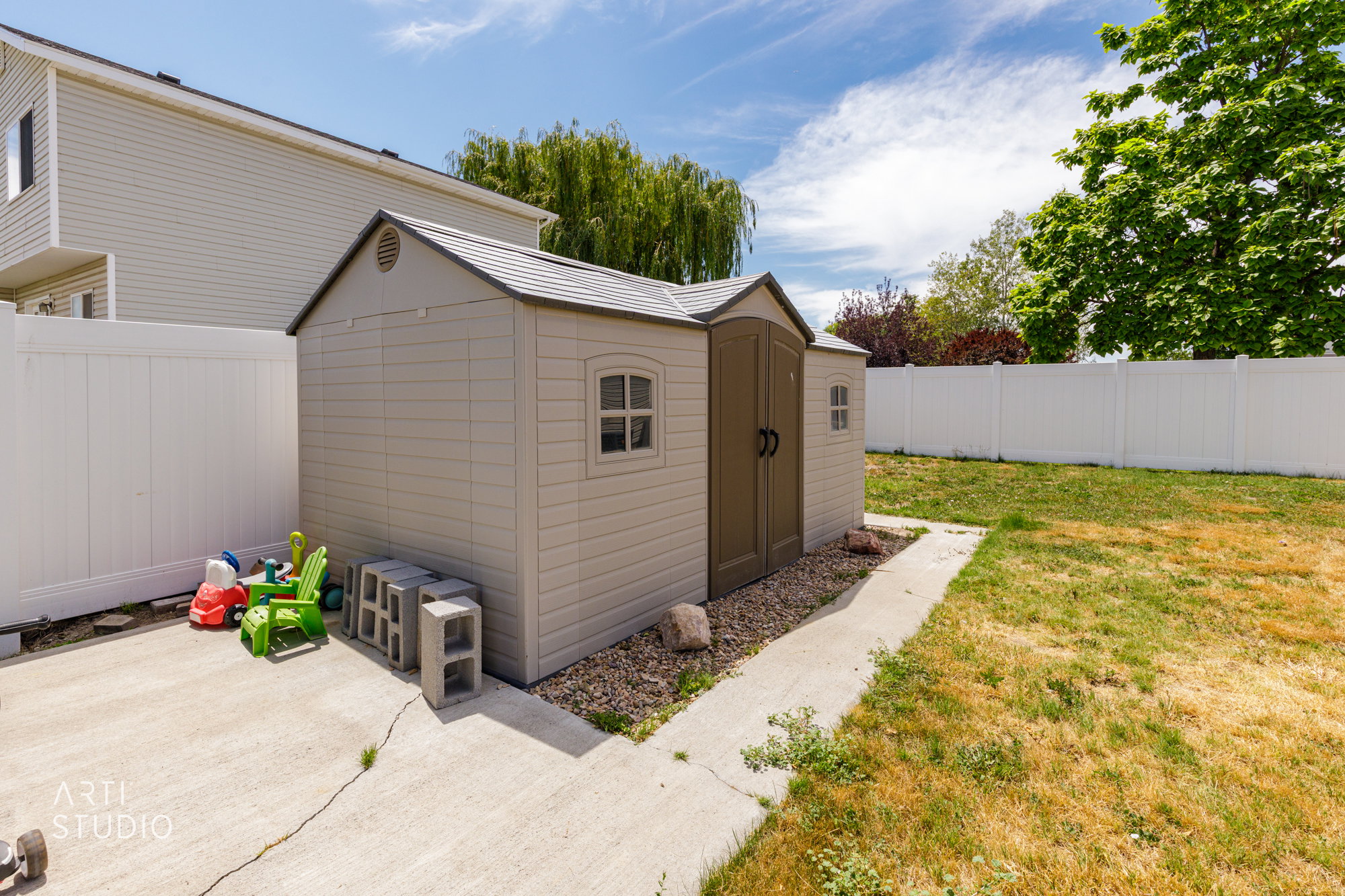 Backyard storage shed on a concrete pad, featuring dual doors and side windows