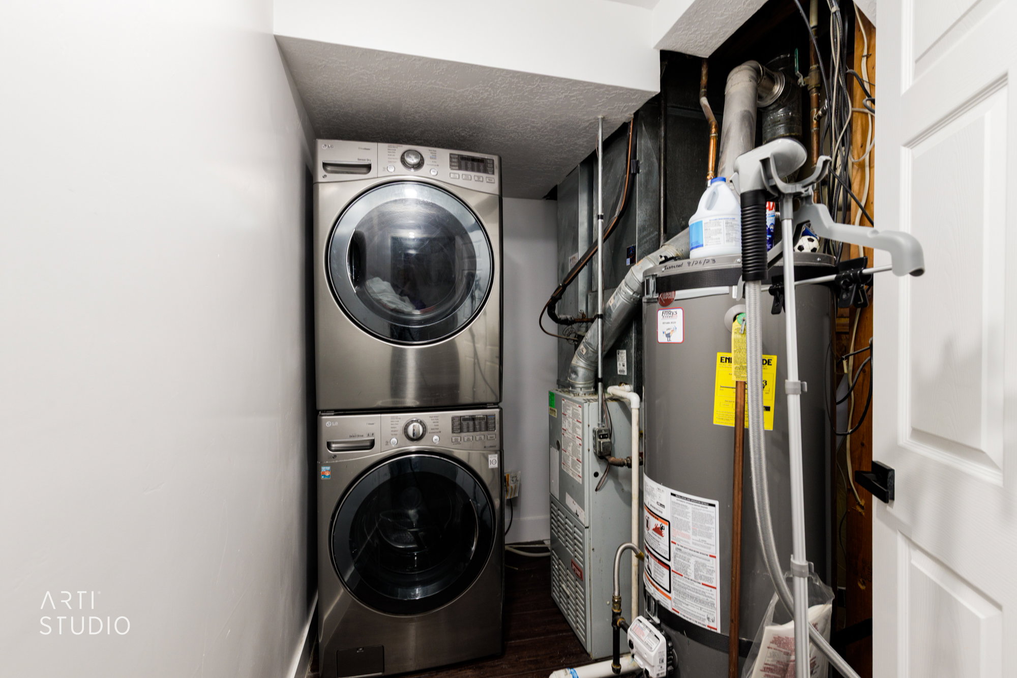 Dedicated utility area featuring a stacked washer and dryer, water heater, and furnace