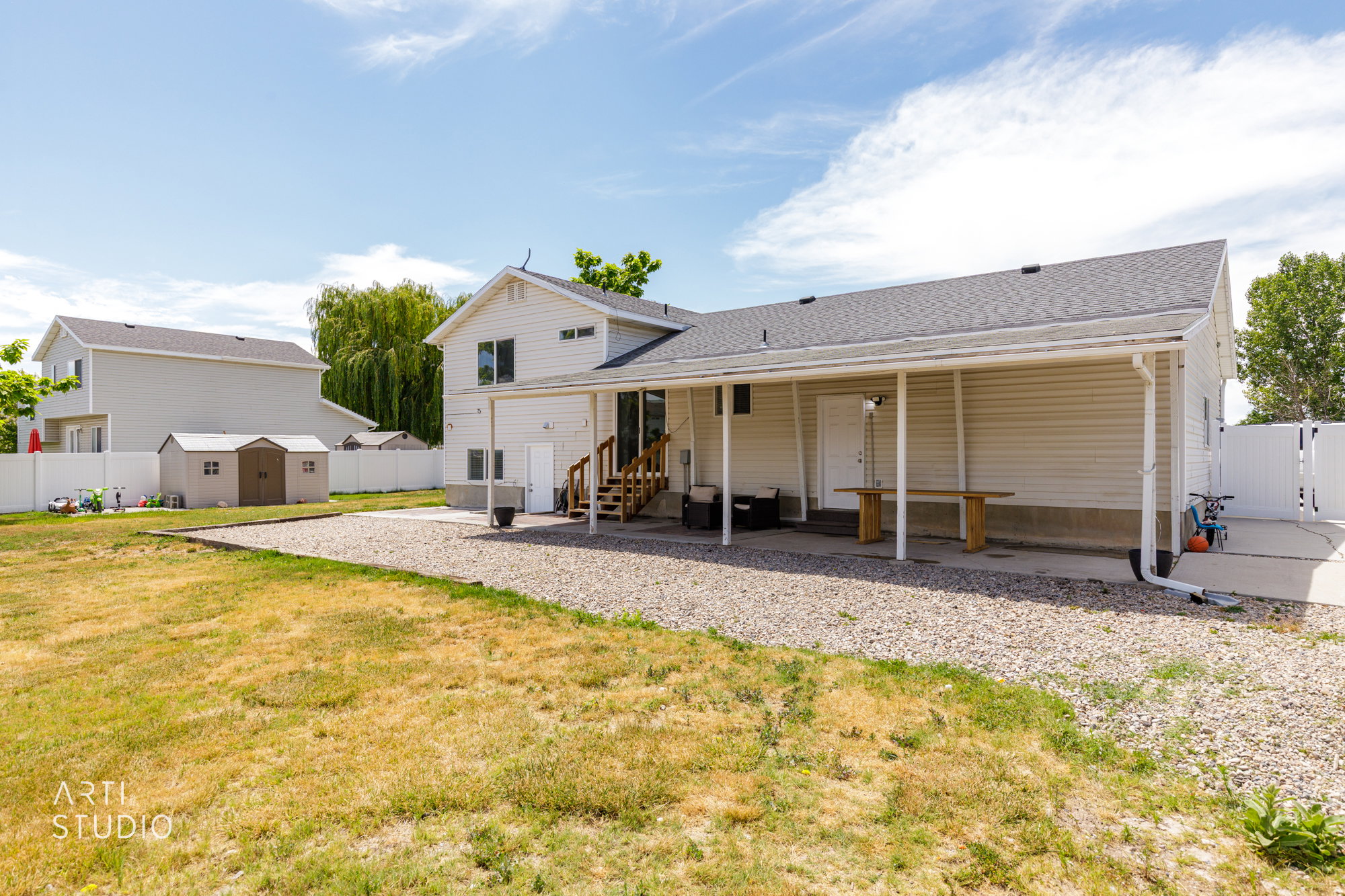 Rear exterior featuring a covered patio, gravel hardscaping, and a fully fenced yard