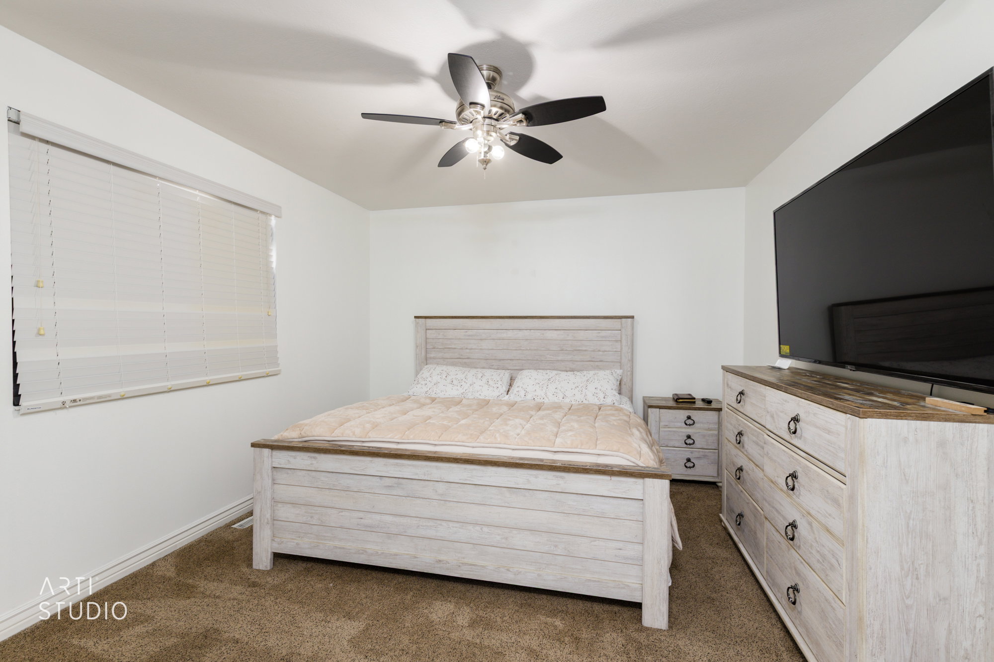 Bright room featuring a window with horizontal blinds, a ceiling fan with integrated lighting, and carpeted flooring