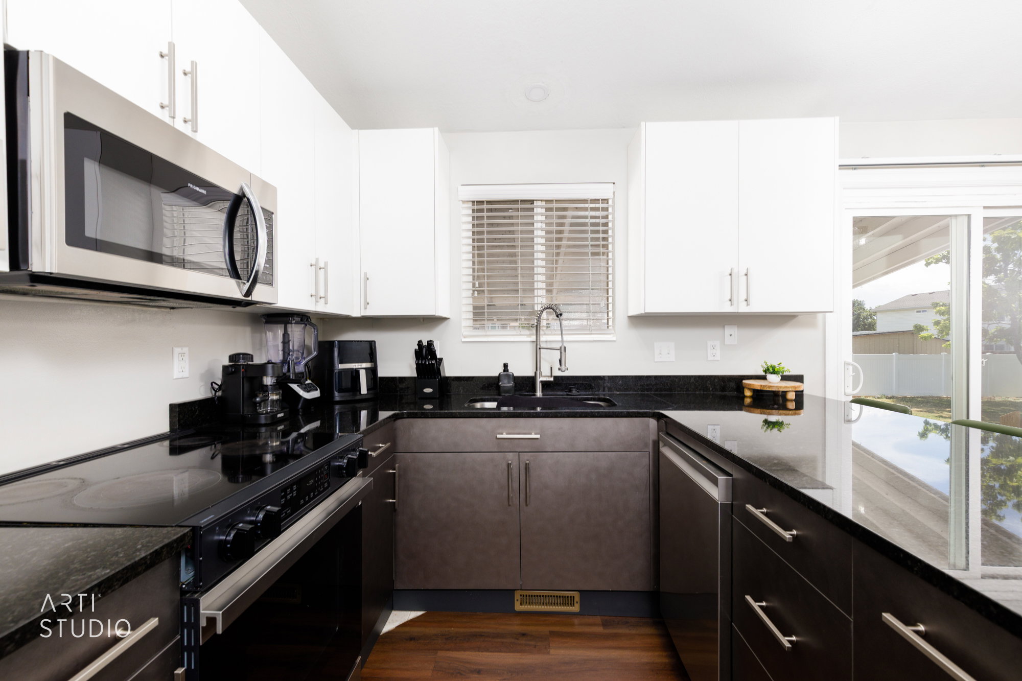U-shaped kitchen featuring dark stone countertops, upper white cabinetry, and lower two-tone cabinetry with brushed nickel hardware