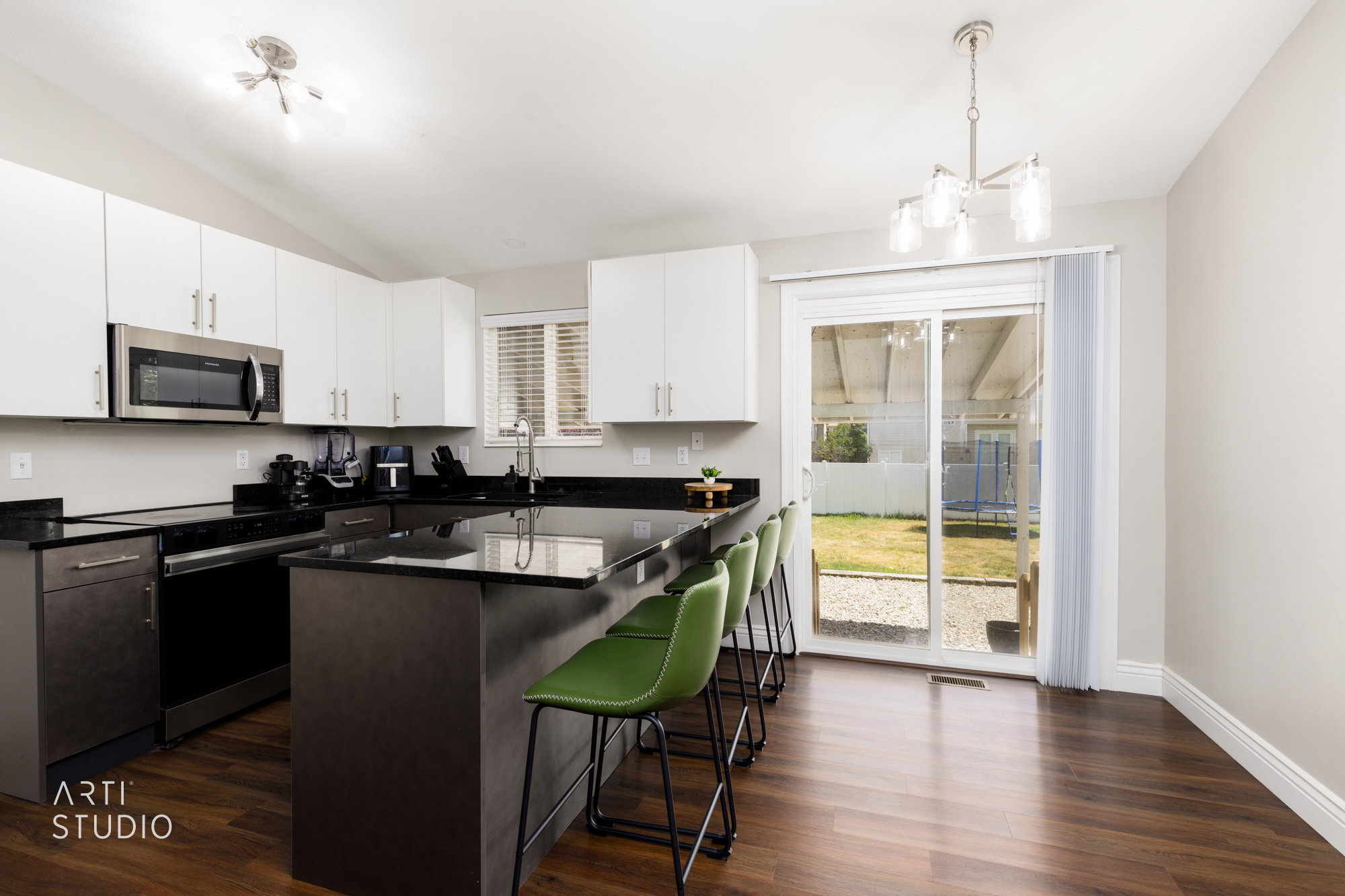 Kitchen featuring wood-finish flooring, white cabinetry, dark countertops, and stainless steel appliances