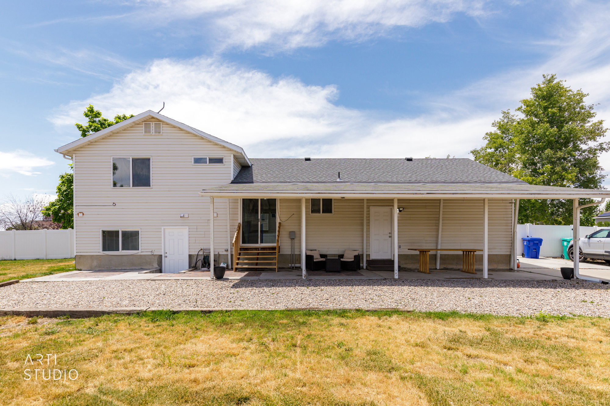 Rear exterior featuring light-colored siding, a covered patio, and a gravel ground cover