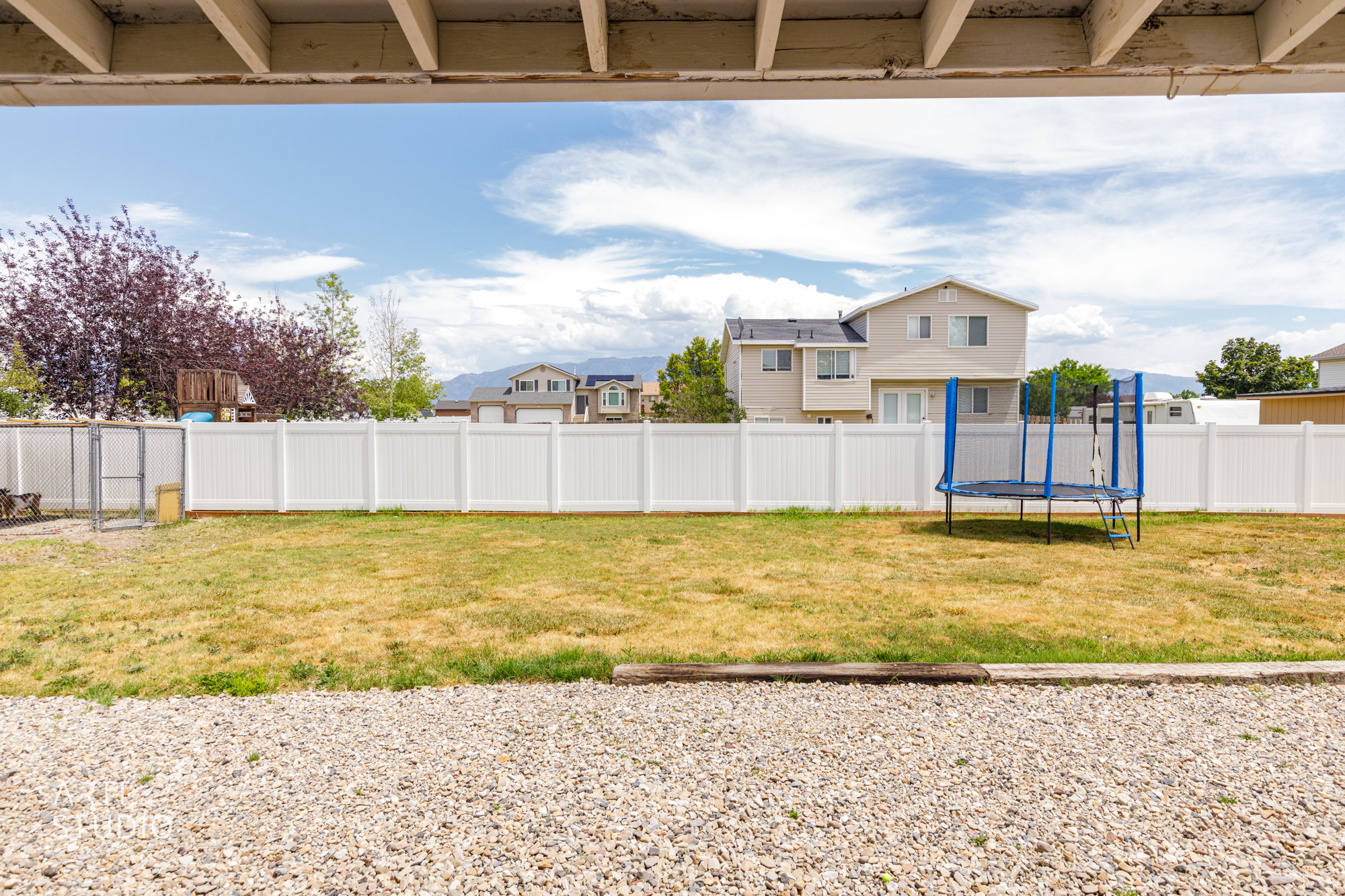 Expansive backyard with a full privacy fence and gravel patio area