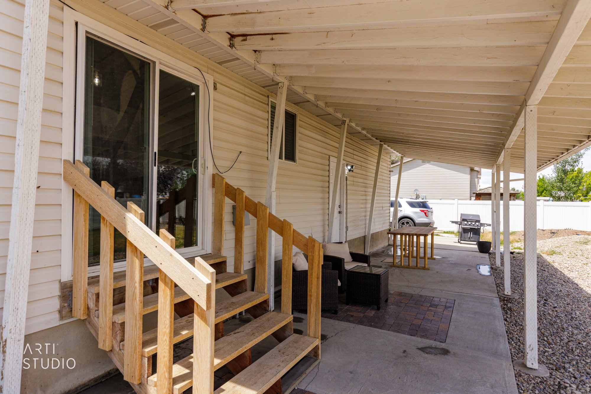 Covered patio area featuring a concrete slab, a small section of paver stones, and an exterior door