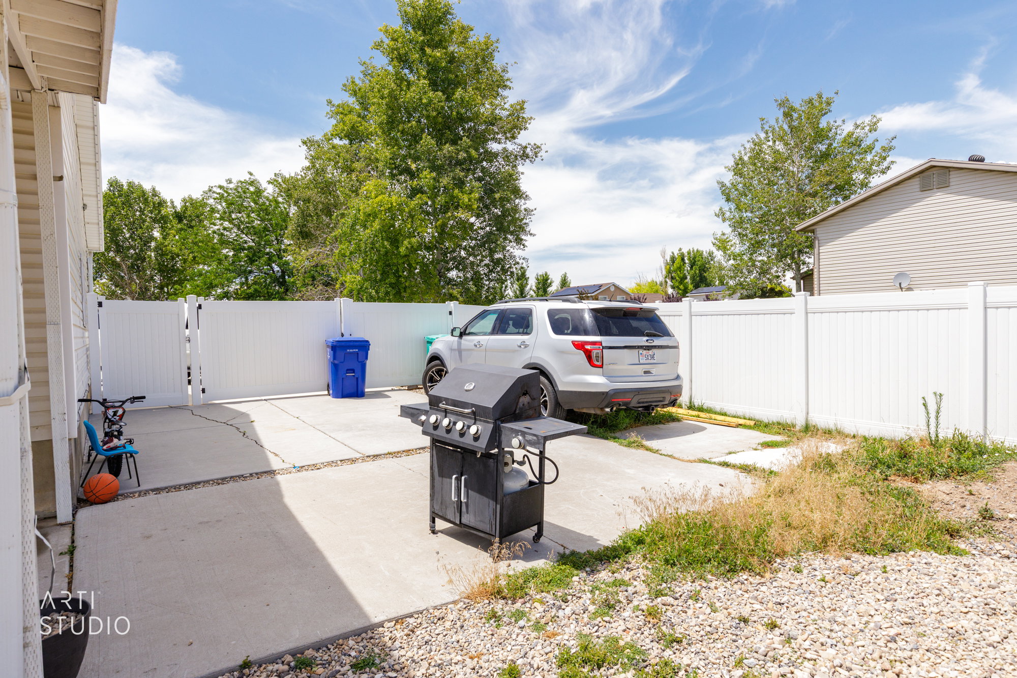 Paved patio space featuring a white vinyl privacy fence and a rear access gate