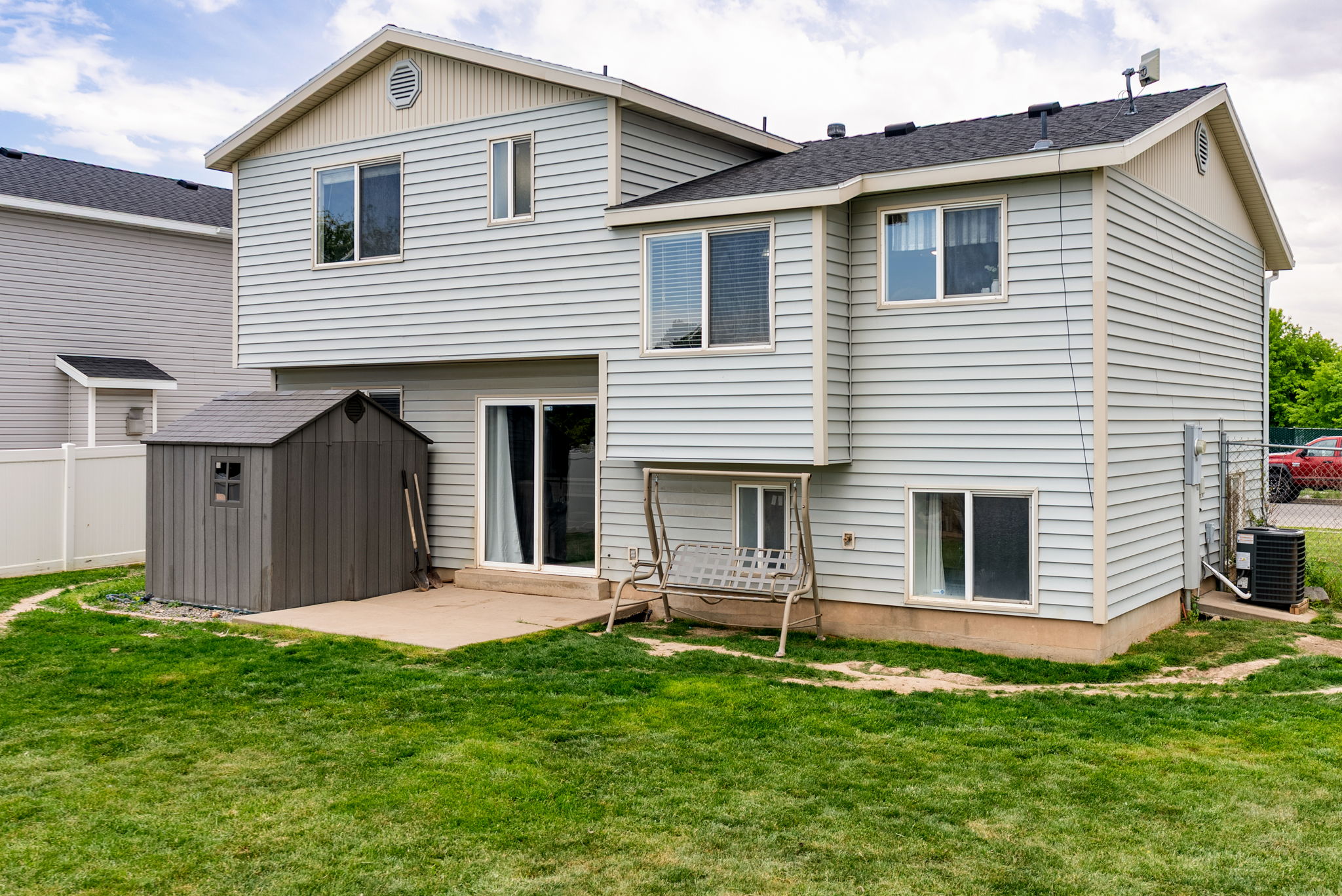 Rear exterior featuring light-colored siding, a concrete patio, and an external storage shed