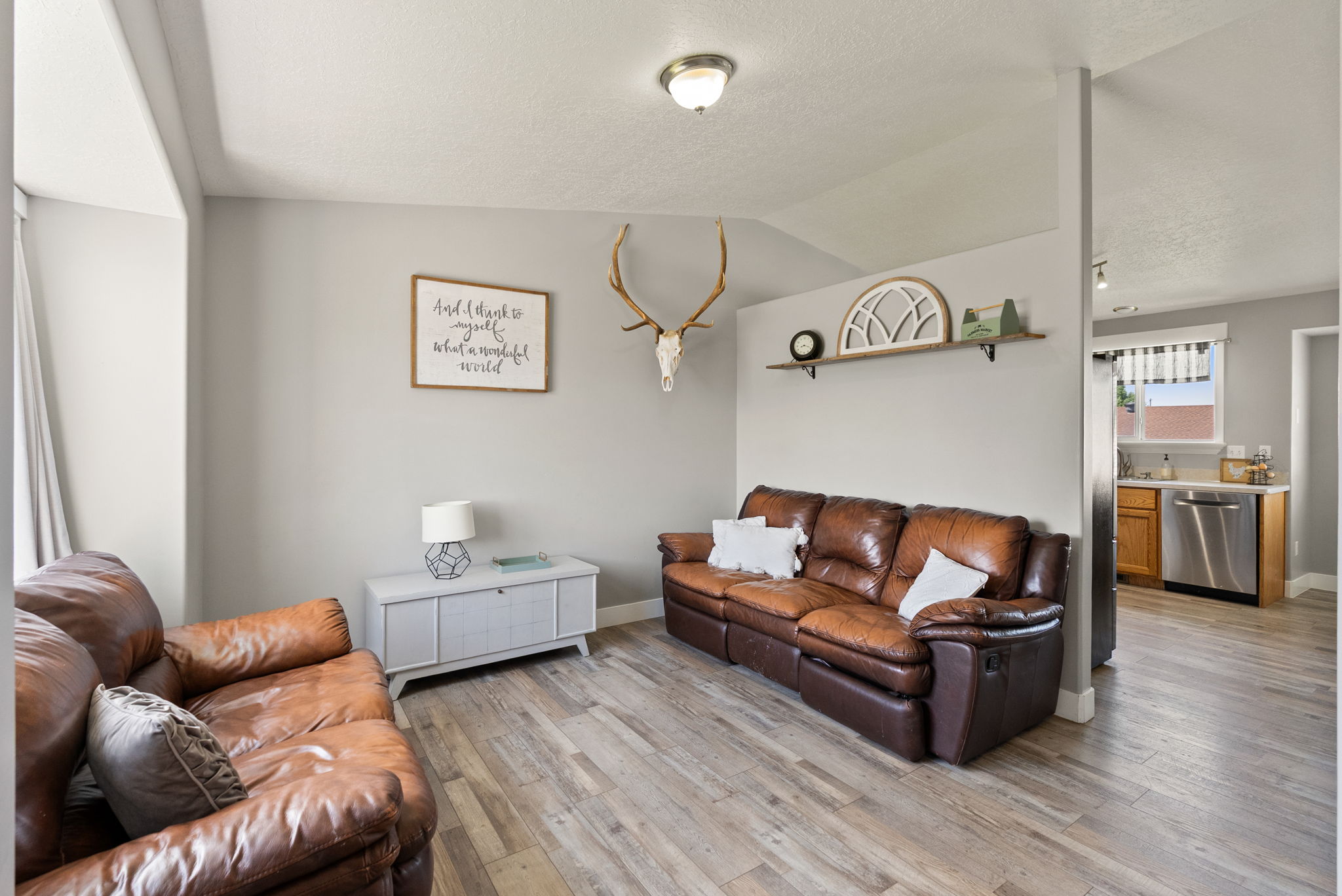 Living area featuring wood-finish flooring, light gray wall paint, and a built-in floating shelf