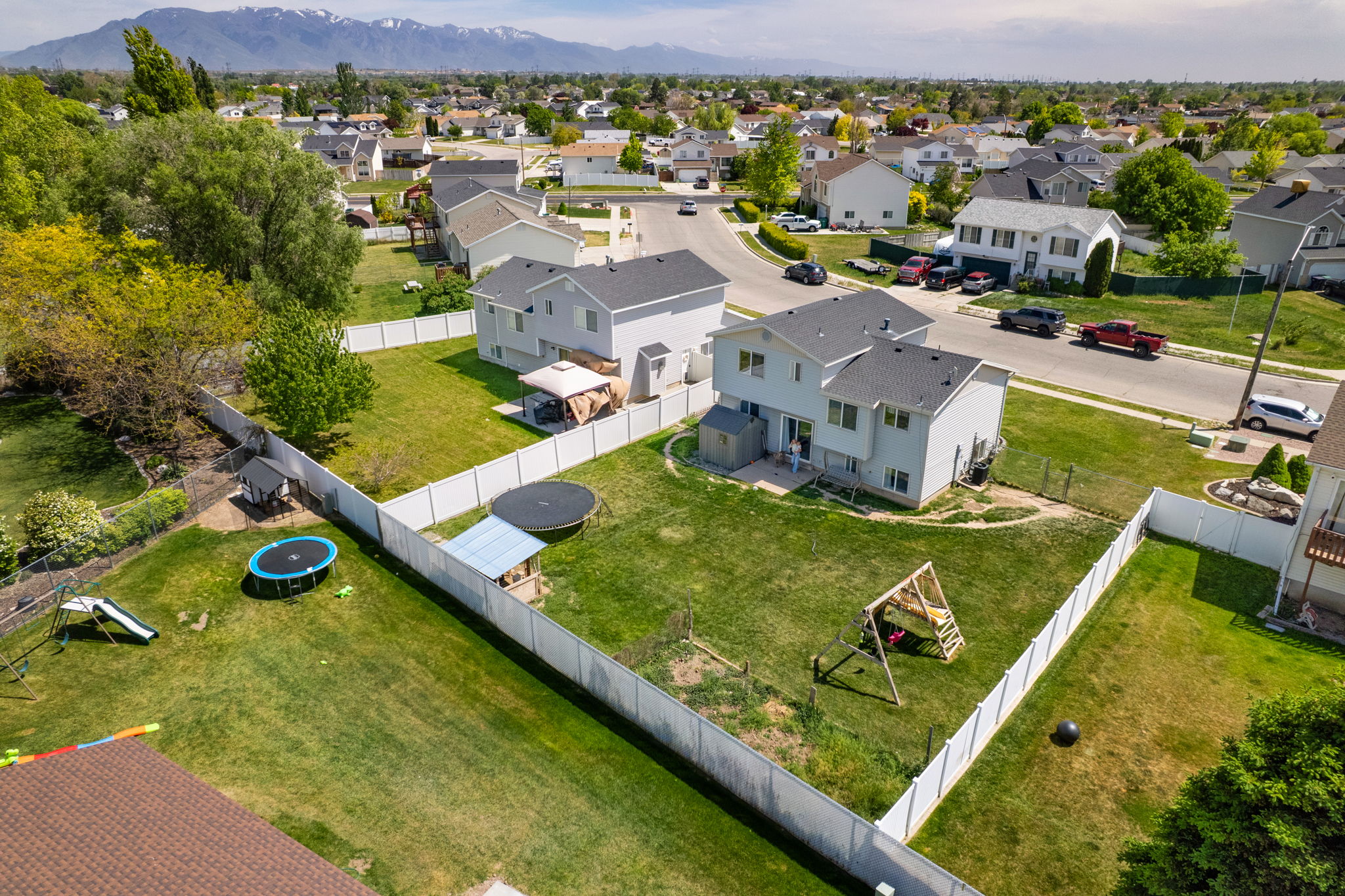 Expansive backyard featuring a manicured lawn, a full privacy fence, and mature trees outlining the property