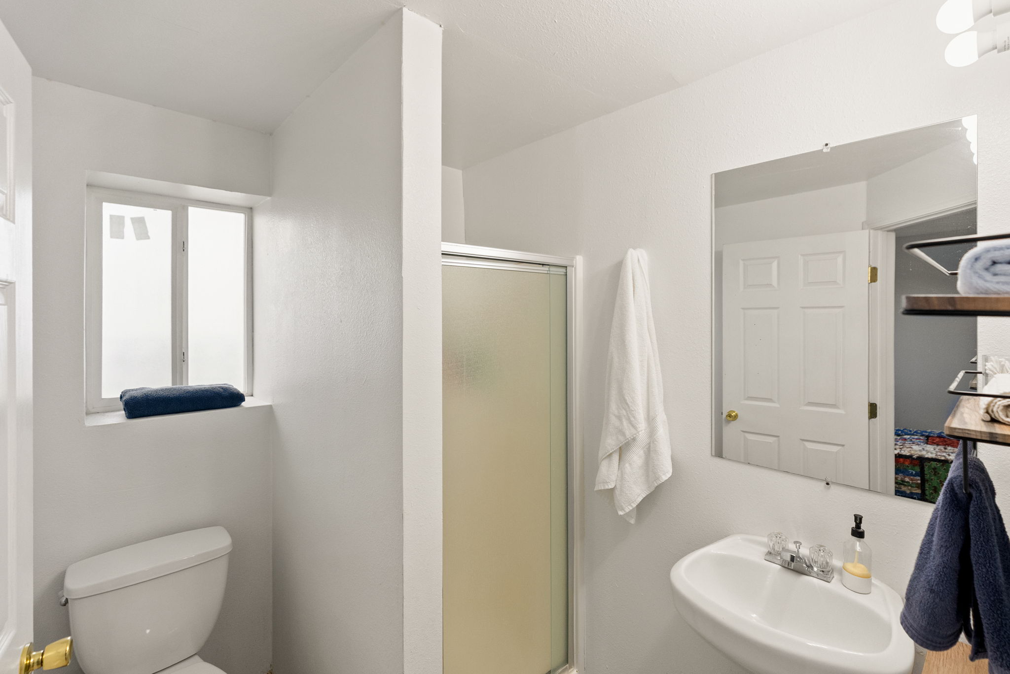 Bathroom with white walls and a frosted window