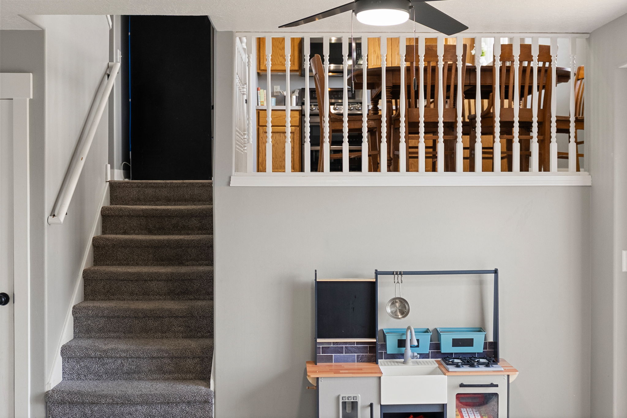Carpeted staircase with white trim and handrail, featuring a dark door at the top landing