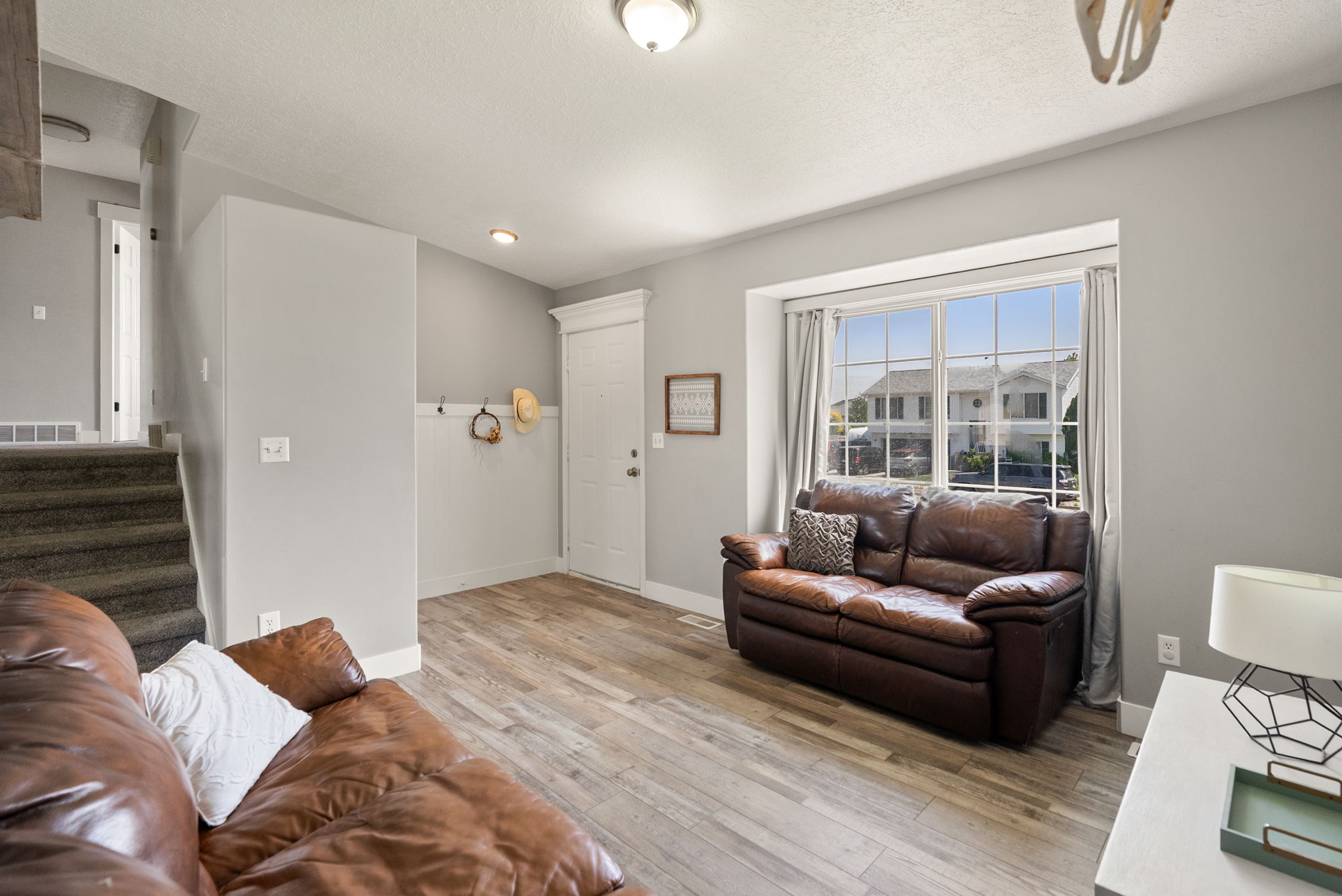 Entry area with wood-finish flooring, staircase with carpeted treads, and a front door featuring transom-style detailing