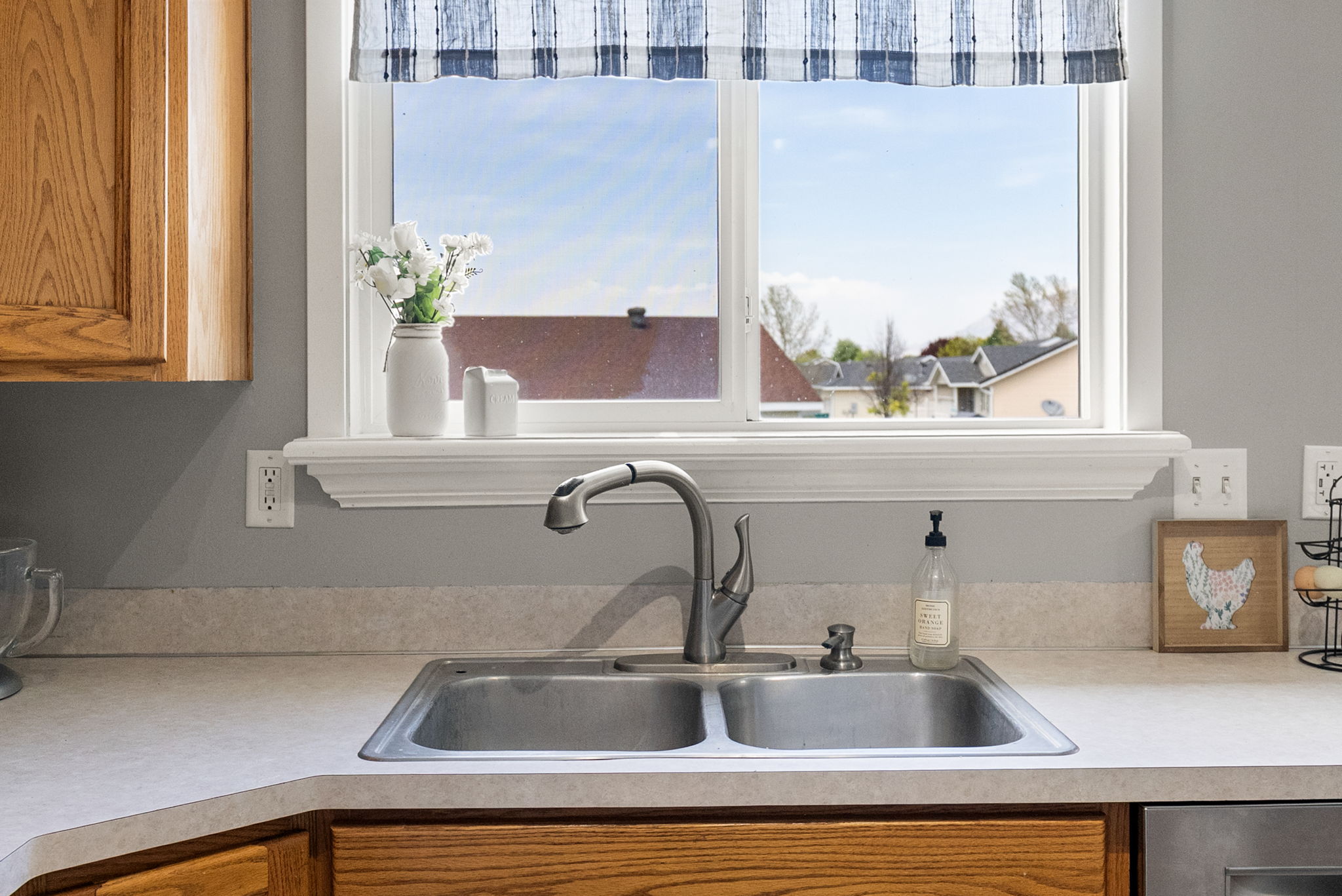 Kitchen featuring a double basin stainless steel sink with a high-arc faucet, set into a light-toned countertop