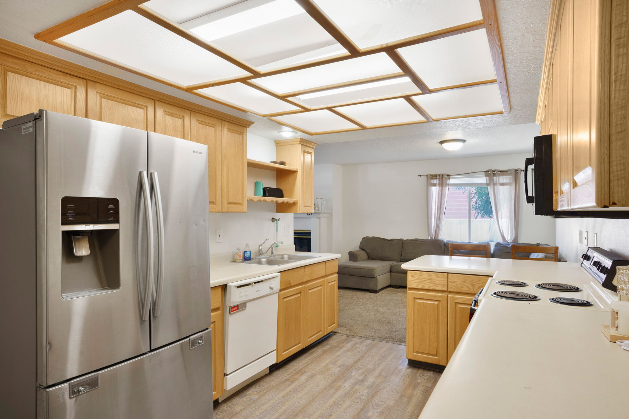 Kitchen featuring light wood cabinetry, a stainless steel French door refrigerator, white countertops, and wood-finish flooring