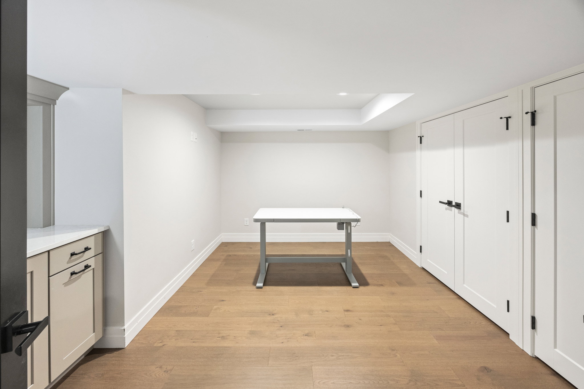 Versatile room featuring wood-finish flooring, recessed lighting, and a tray ceiling element
