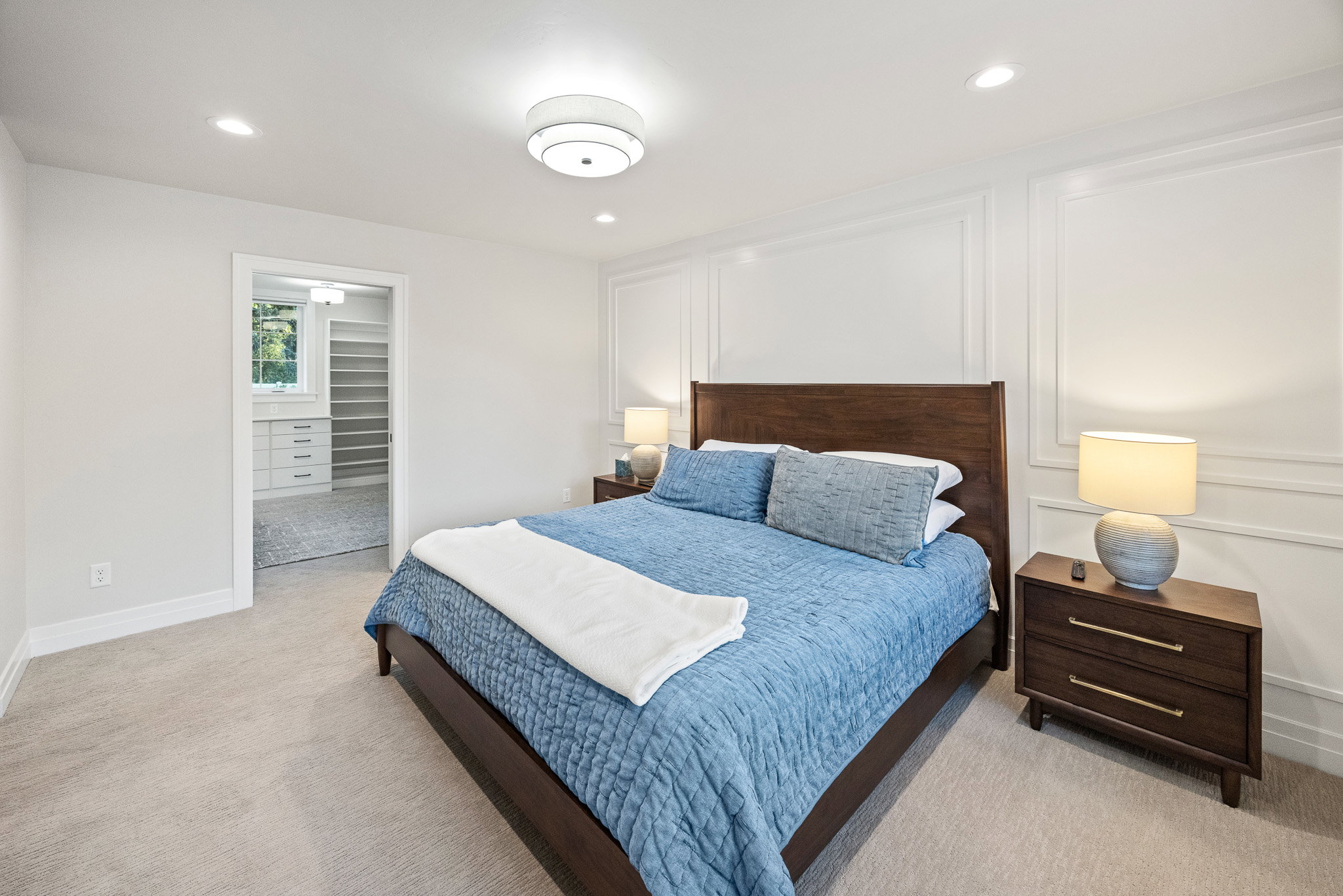 Carpeted room with recessed lighting and a decorative ceiling fixture, featuring a wall with applied molding