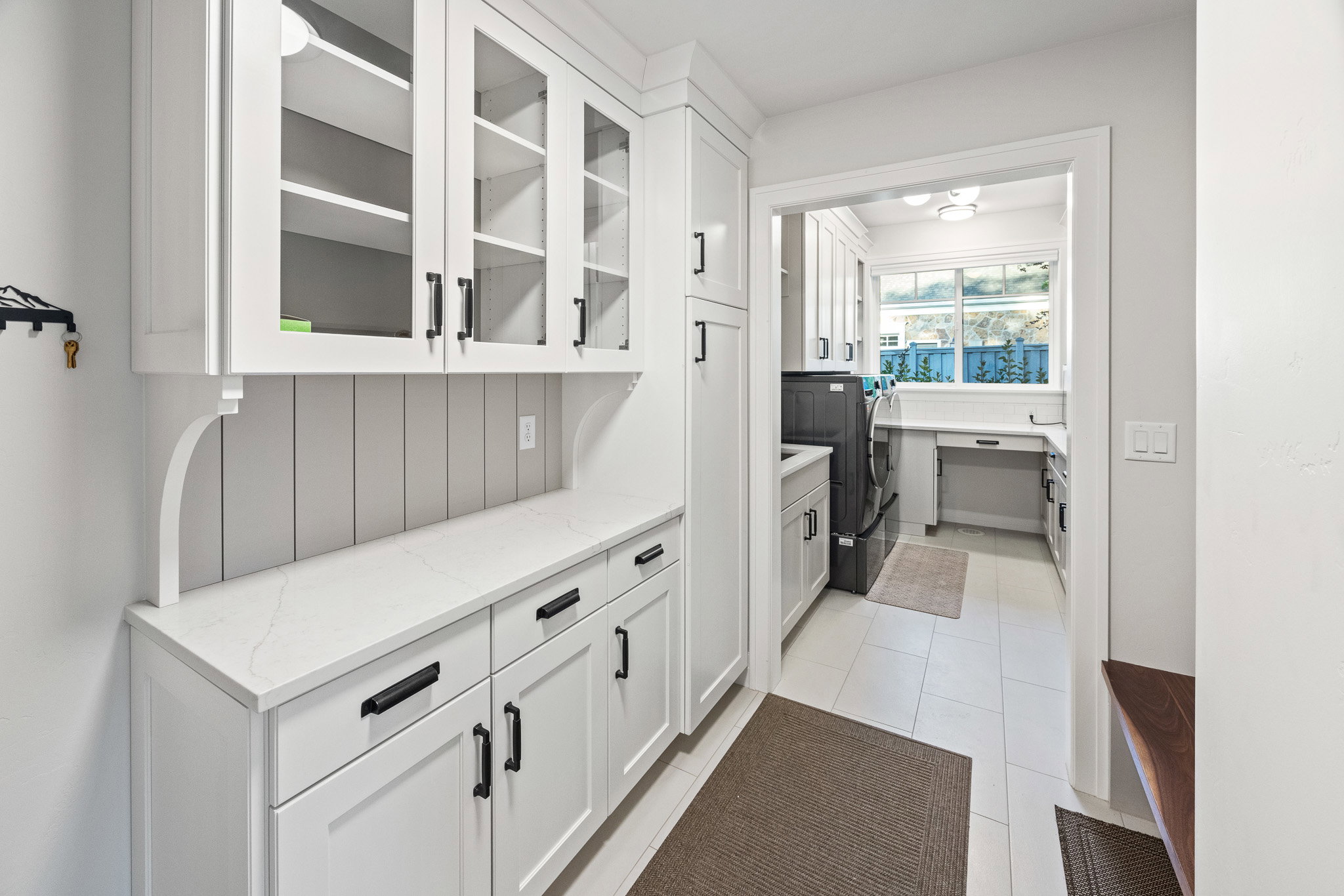 Dedicated utility space featuring white shaker cabinetry, glass-front upper cabinets, a light-toned countertop, and recessed lighting